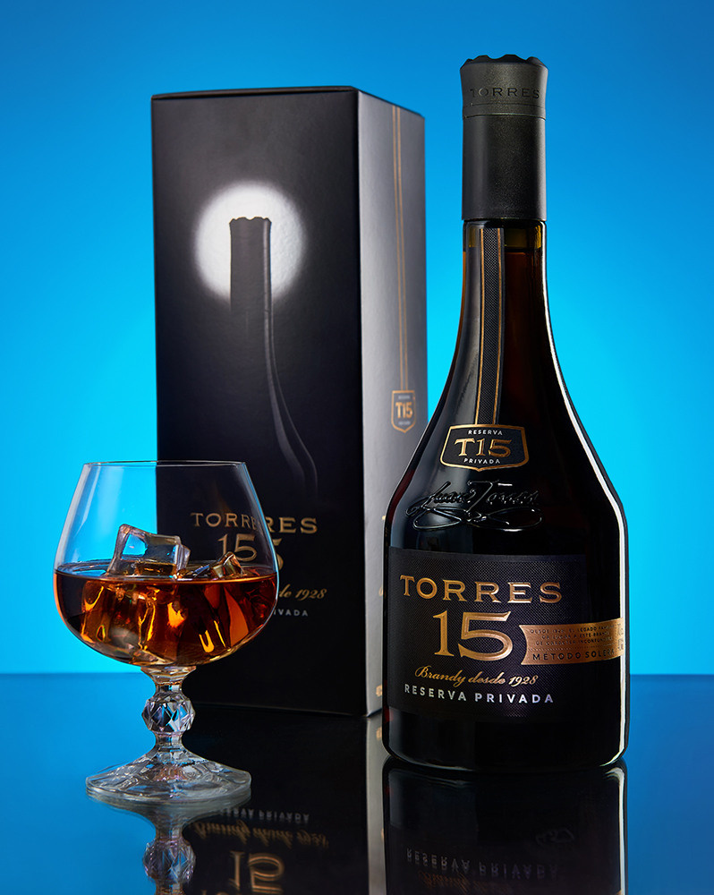 Бутылка коньяка, коробка и фужер - рекламная имиджевая съемка с отражением и подсветкой на фон