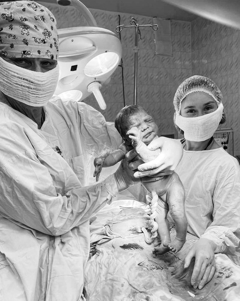 момент рождения малыша, доктор держит в руках новорожденного ребенка