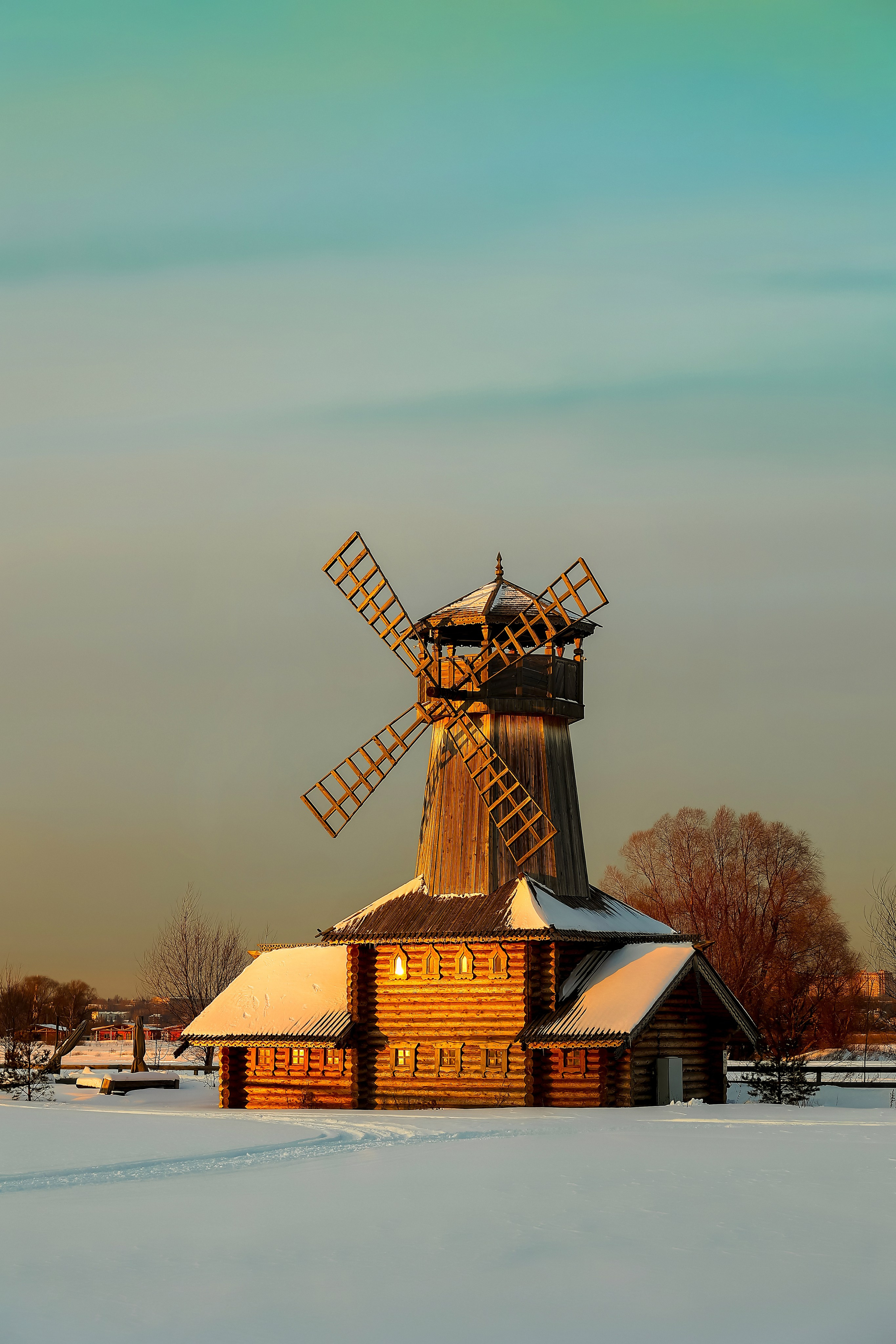 Та же мельница с другого ракурса в более тёмном вечернем свете, солнце почти за горизонтом, длинные тени ложатся на ровный снег.