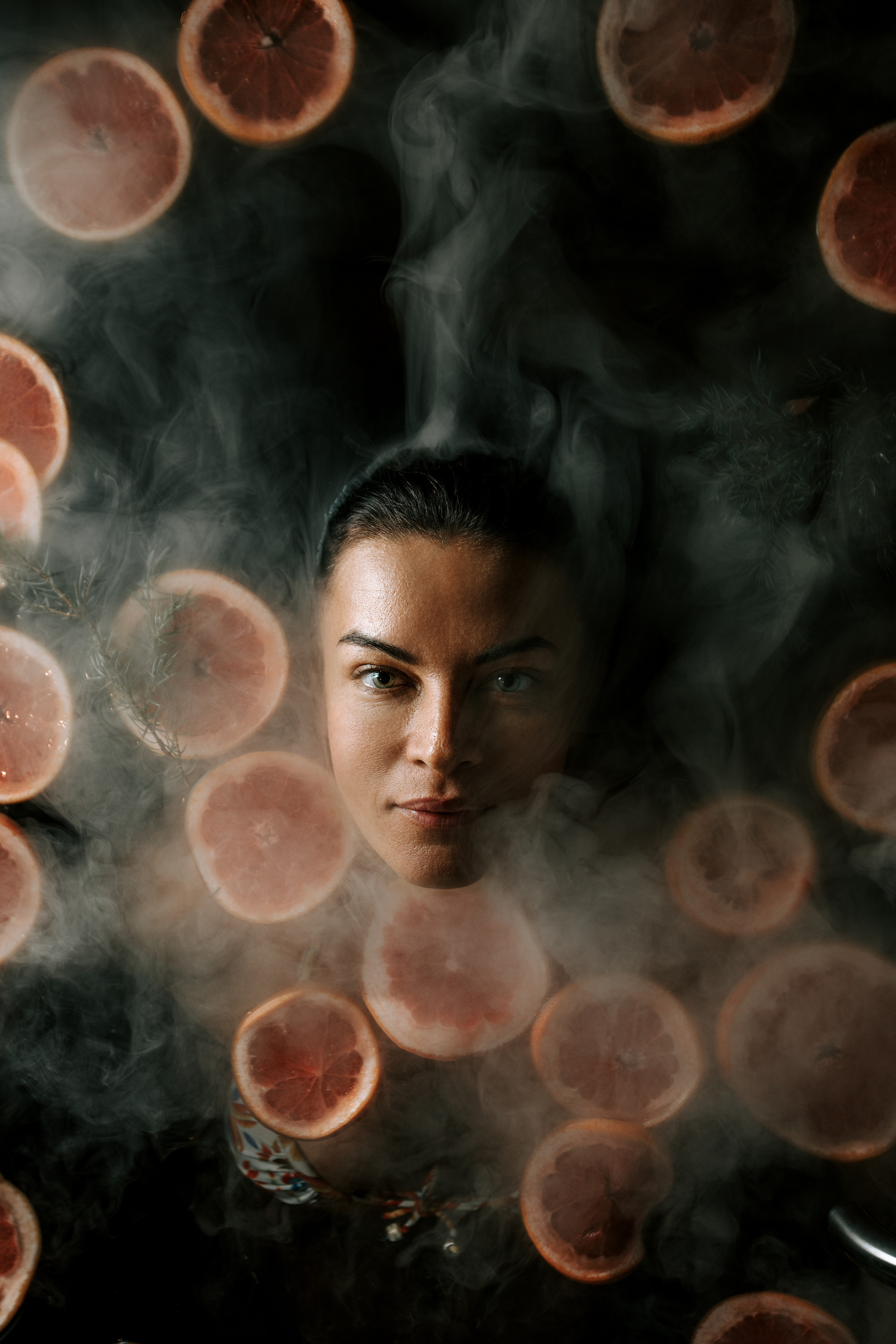 крупный план лицо в воде среди фруктов в дыму, взгляд вверх на фоторафа