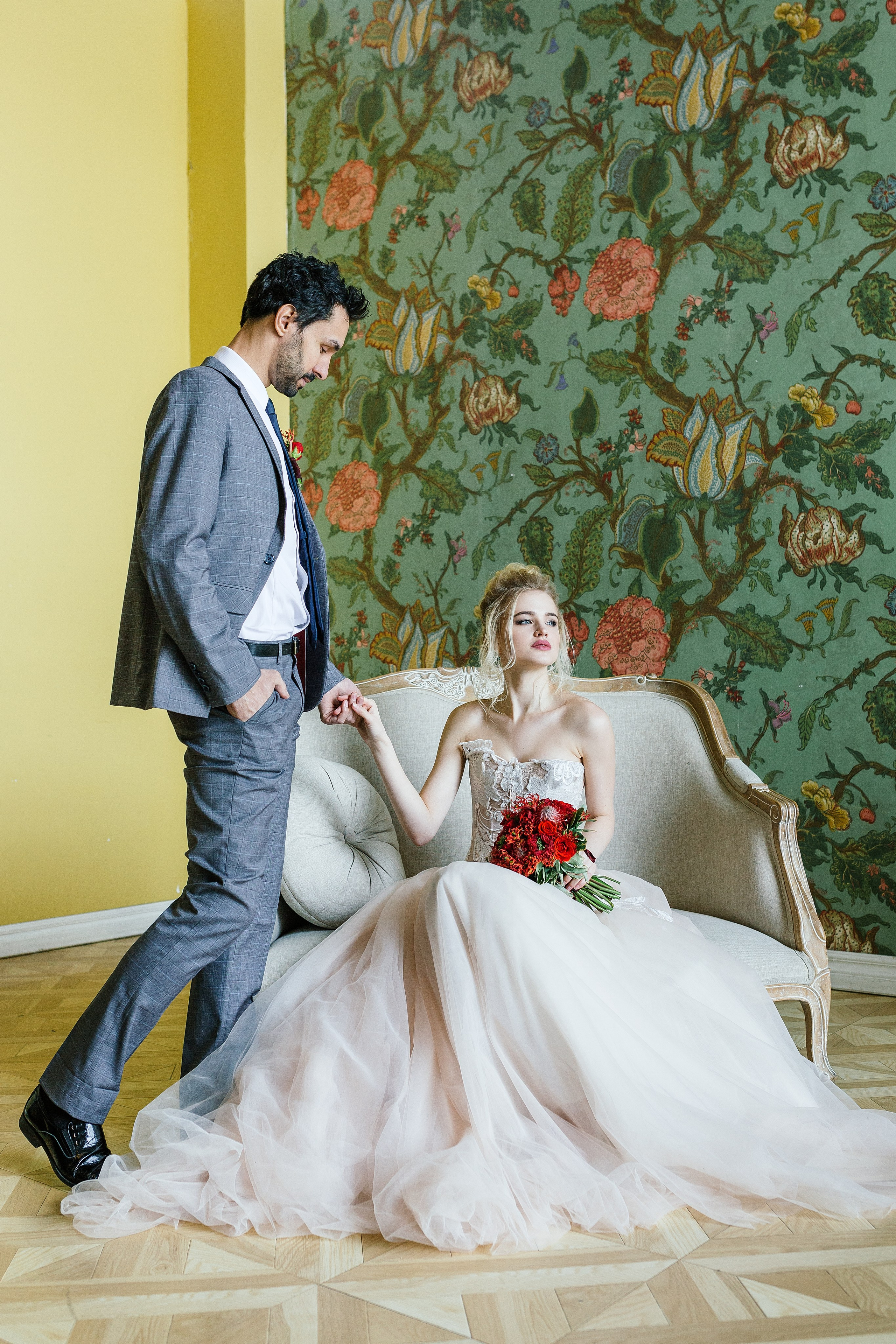 Фотограф свадеб проводит фотосессию в студии города Москвы, в весенний месяц, для молодожен – снимок пары на софе