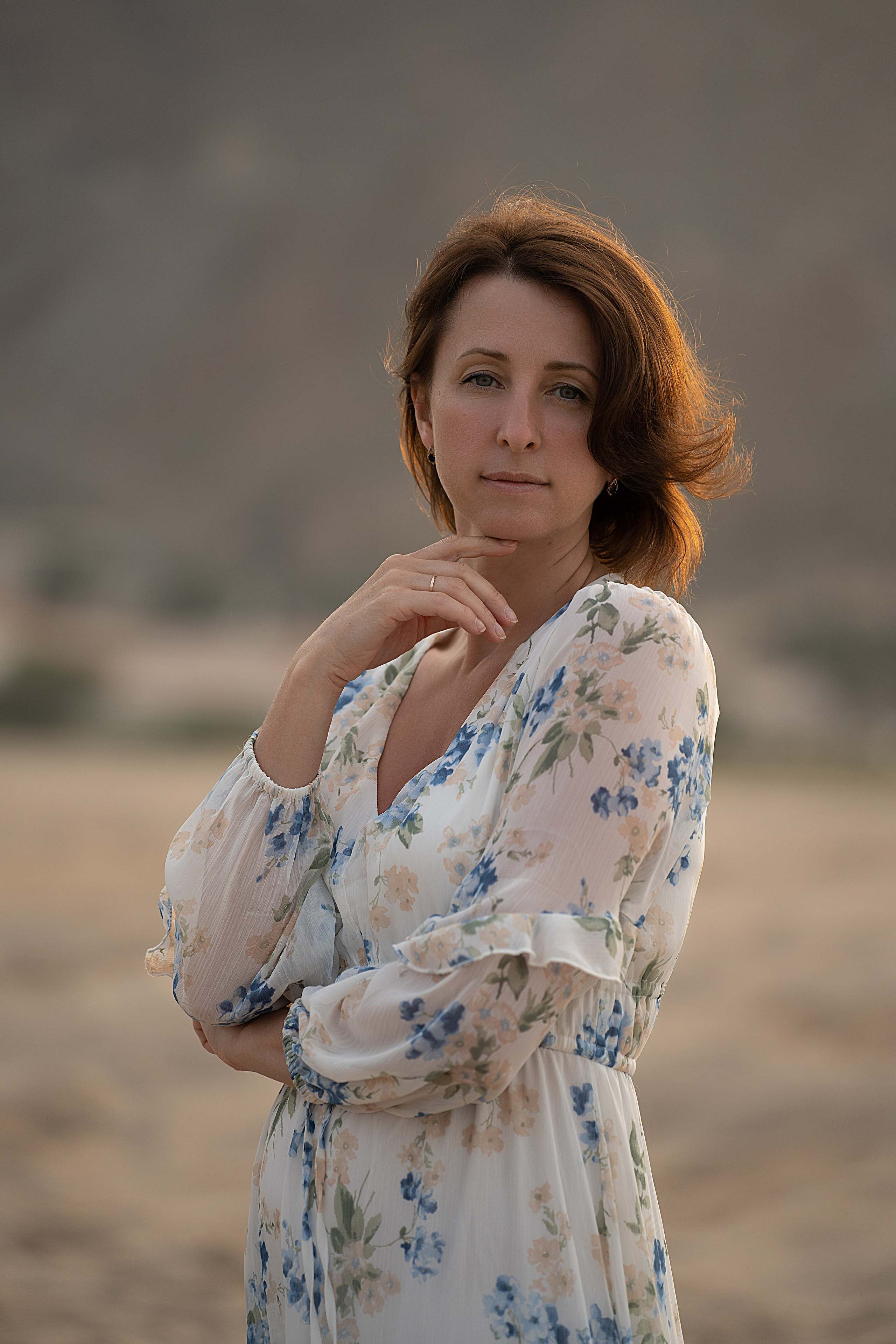 Женский портрет по пояс . Женщина смотрит в кадр и у лица рука.