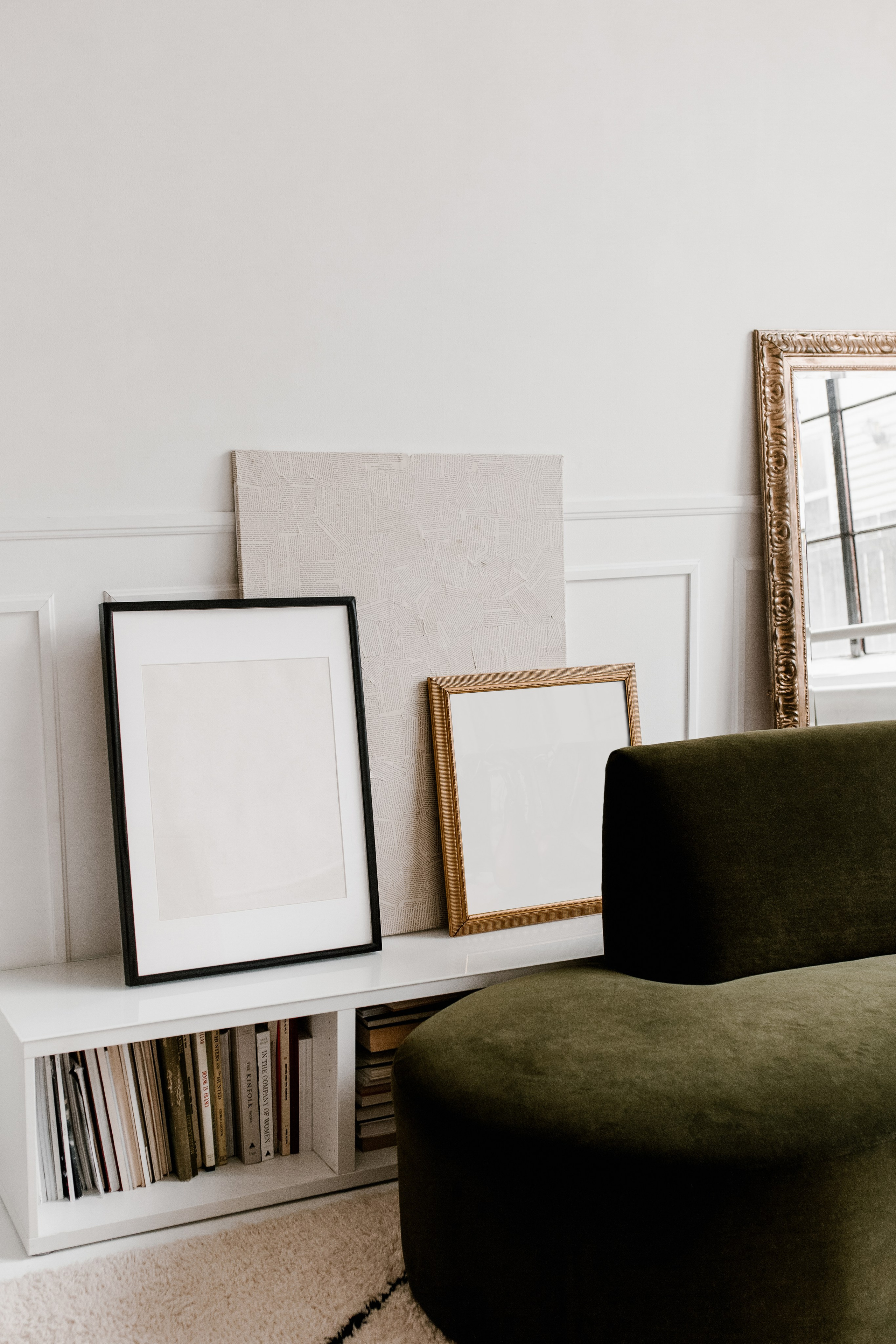 Рамы для картин в интерьере возле стены за зеленым диваном
