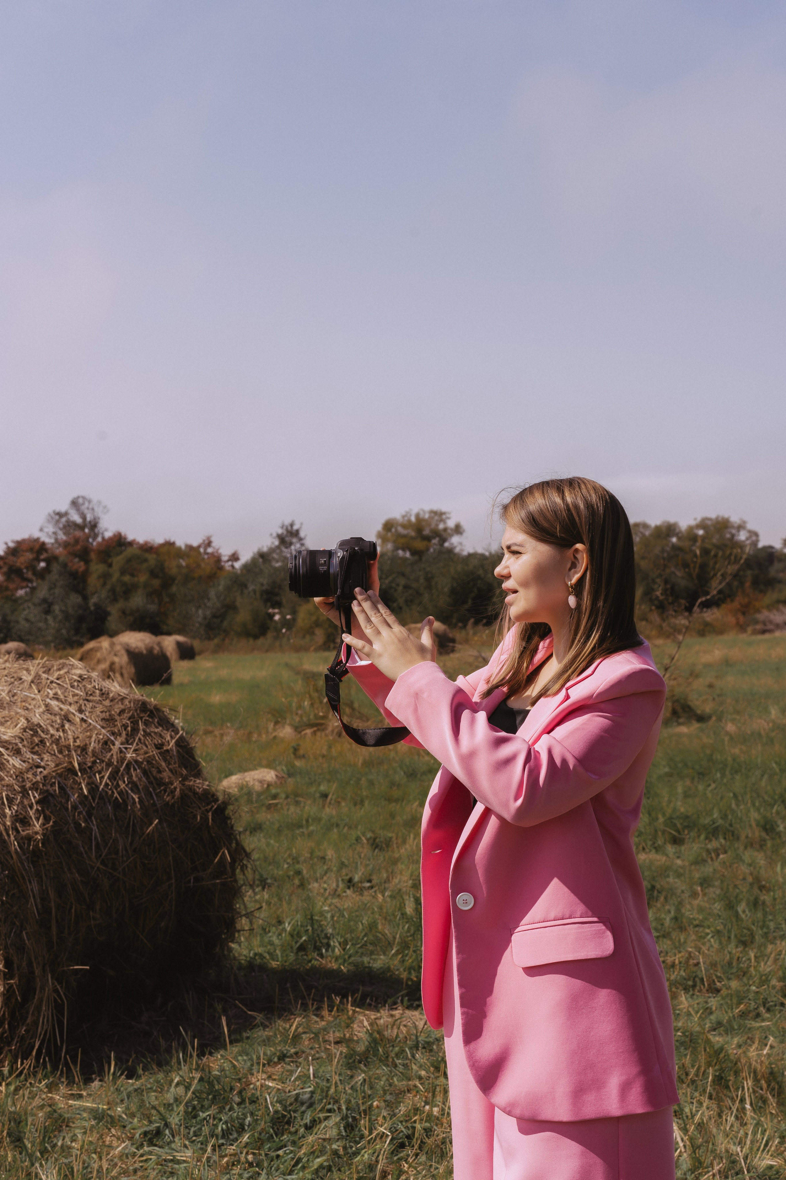 Девушка в белой рубашке рисует на холсте красками в поле с сеном летом в прекрасную летнюю погоду