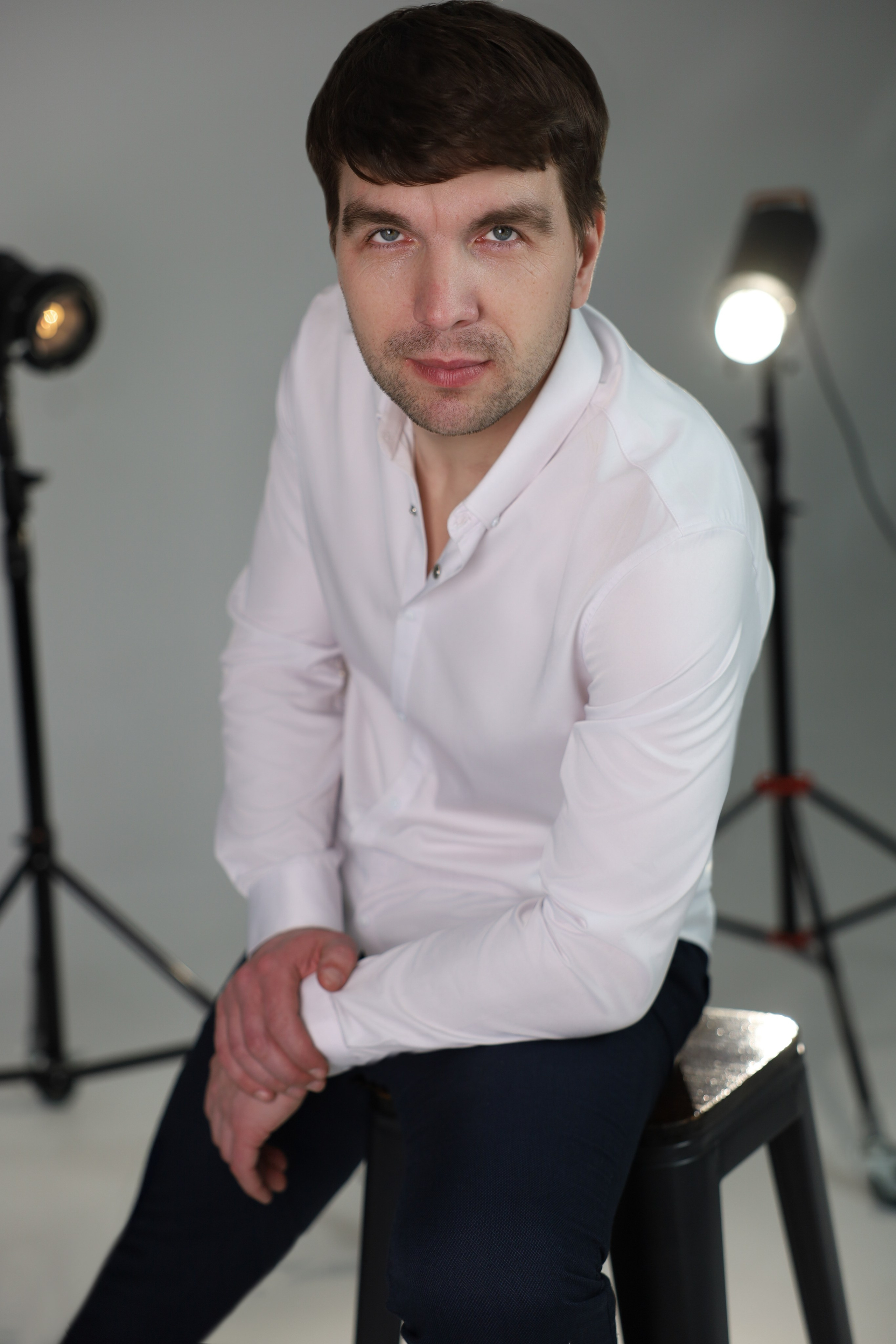 Мужчина в белой рубашке сидит на табурете. Евгений Абзаров Фотограф видеограф 