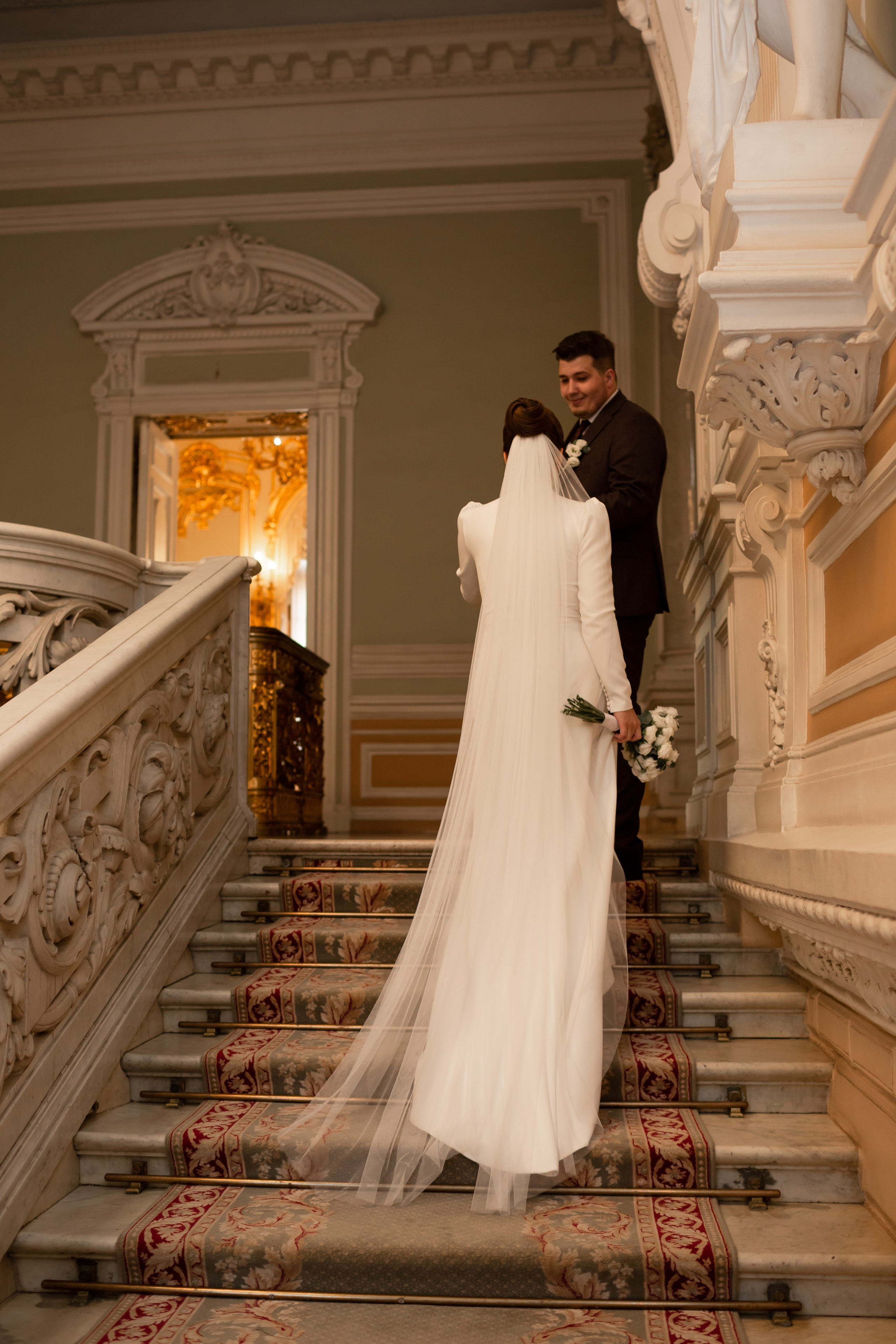 Свадебная фотосессия в Санкт-Петербурге: жених и невеста поднимаются по лестнице дворца.