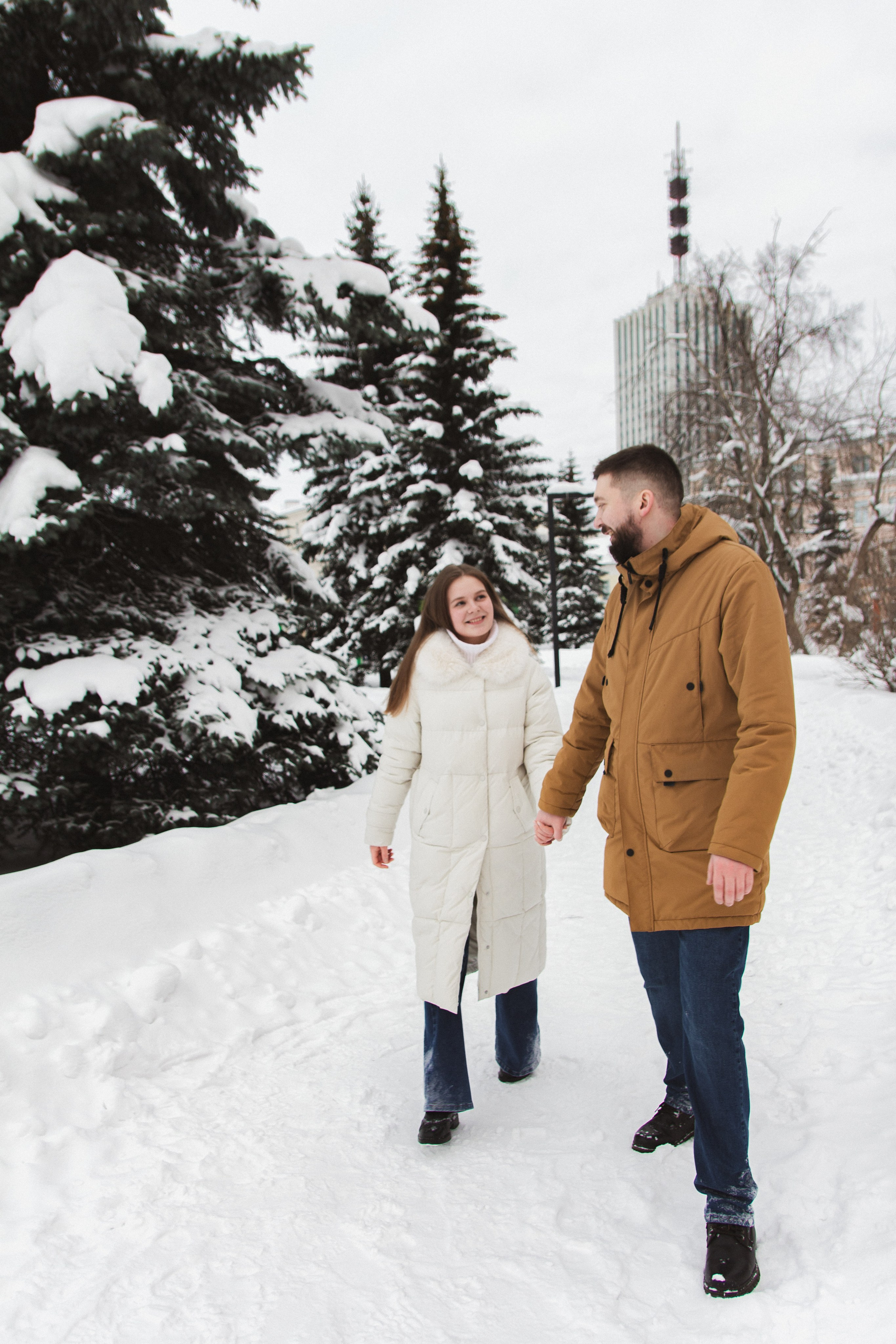 Романтическая фотосессия - пара гуляет по заснеженному парку зимой