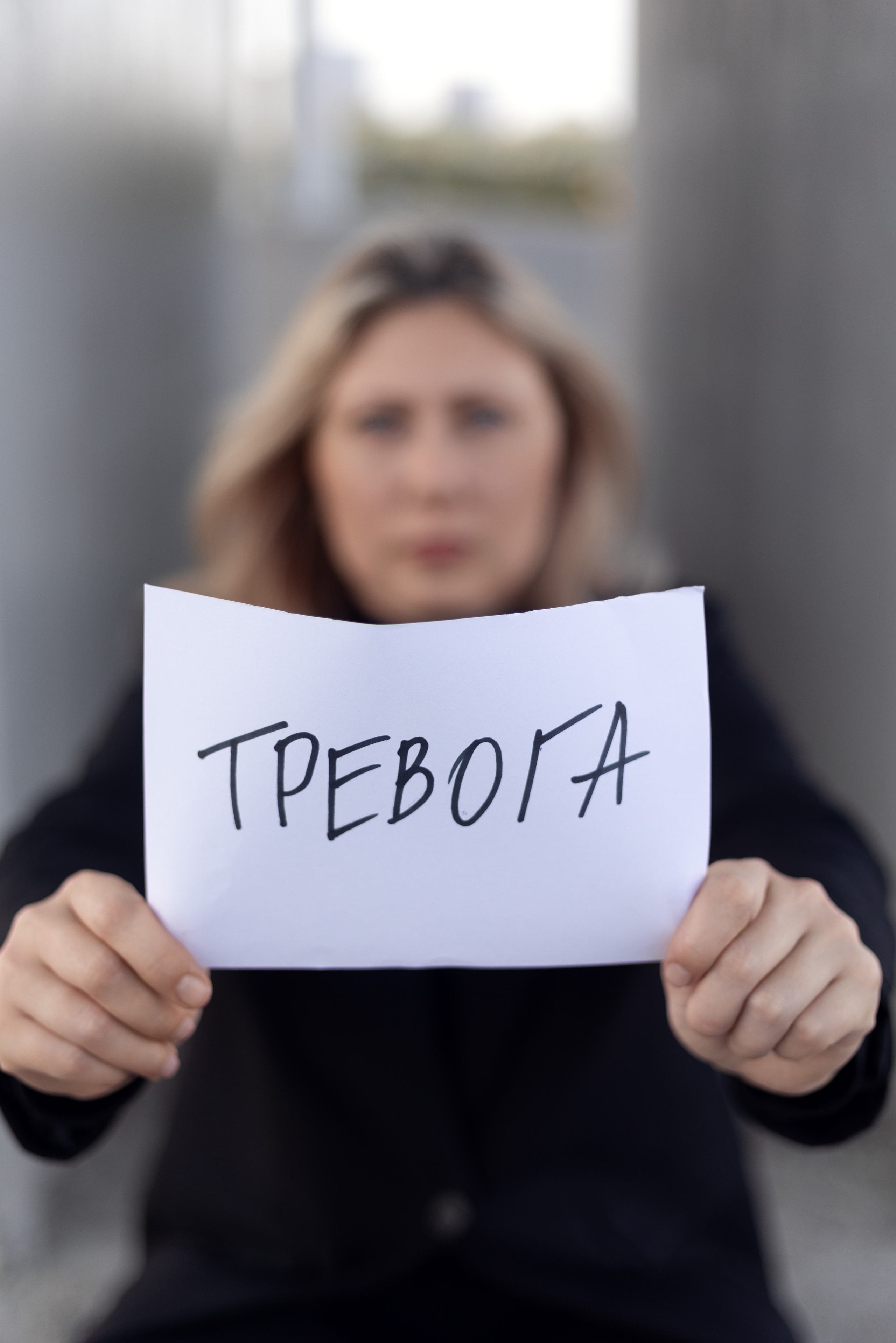 Психолог с табличкой «Тревога» на размытом фоне — фото для блога о психологии в Казани