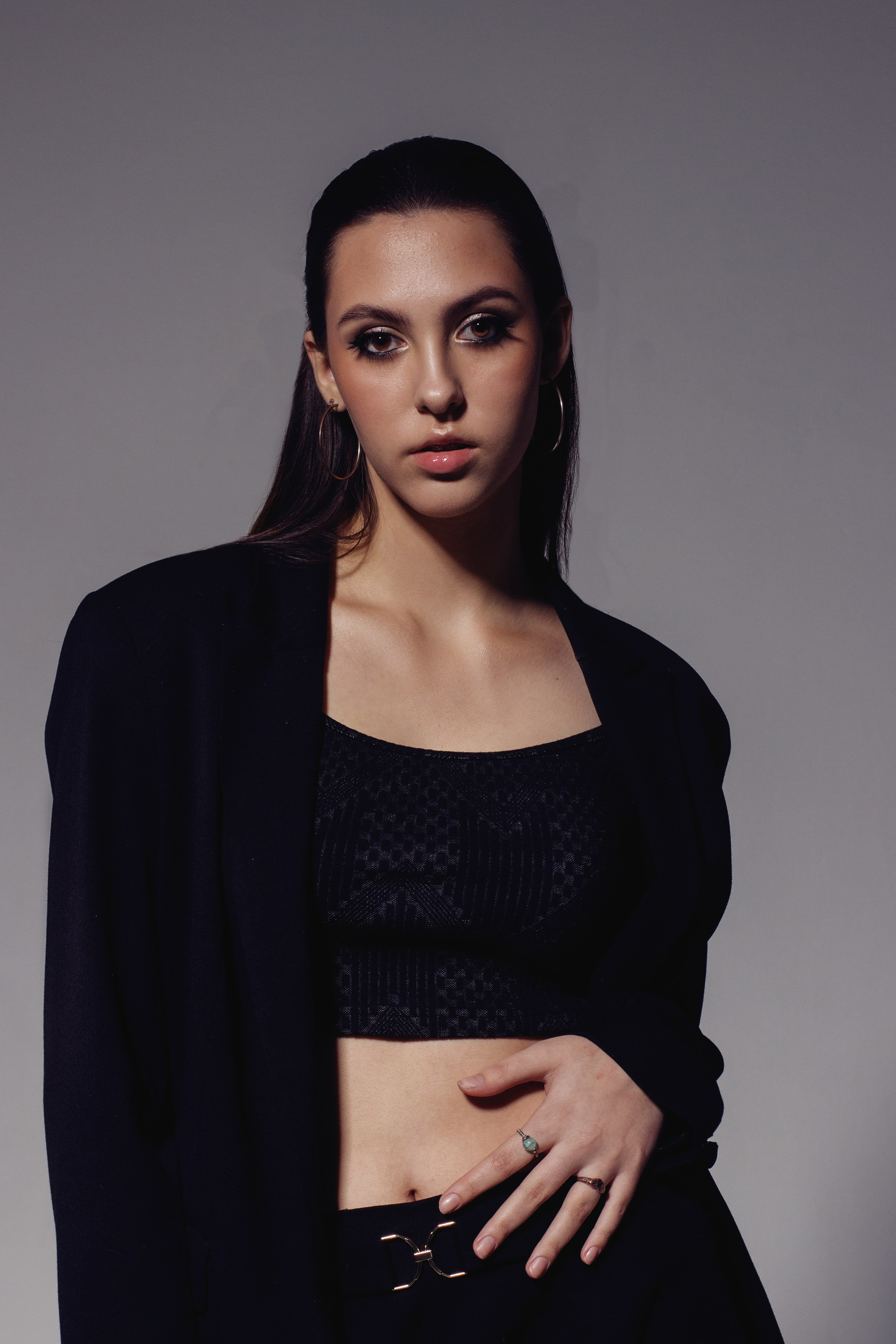 Студийный портрет девушки в чёрном наряде на сером фоне