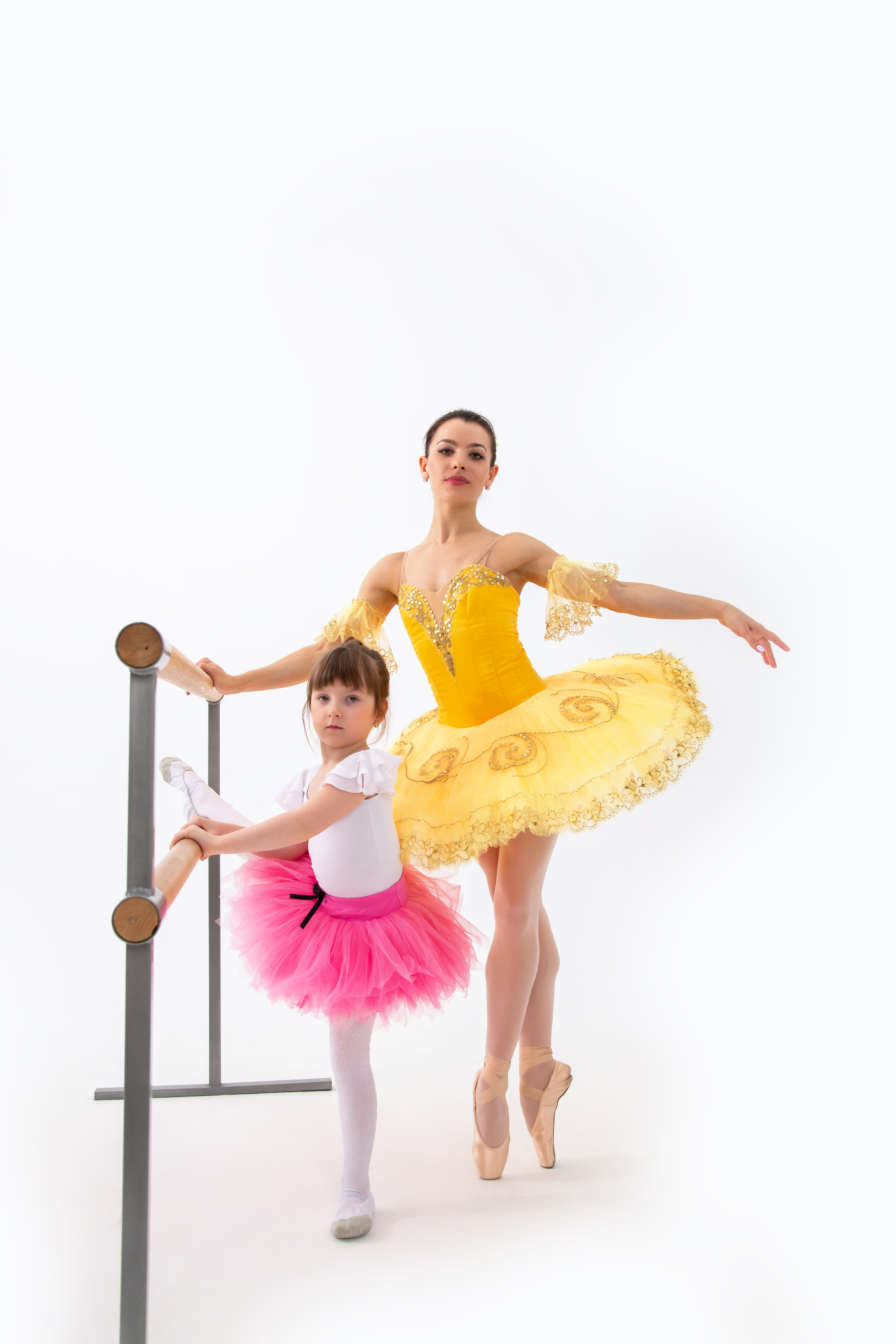 Девочка балерина позирует у станка вместе со своей наставницей балериной  на фотосессии для гимнастики и балета 
