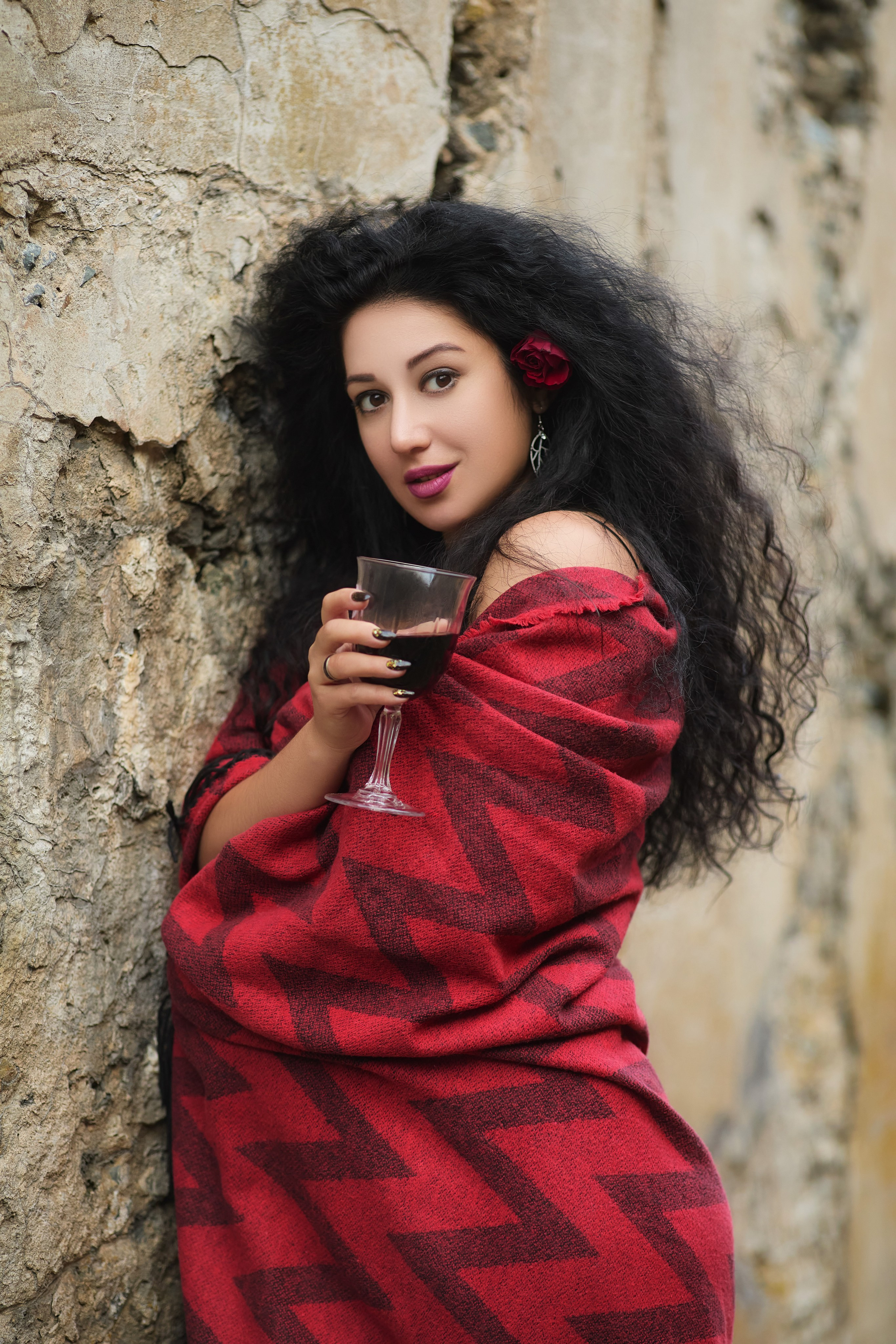 Девушка в красном пледе держит бокал красного вина, позирует на фоне форта во Владивостоке