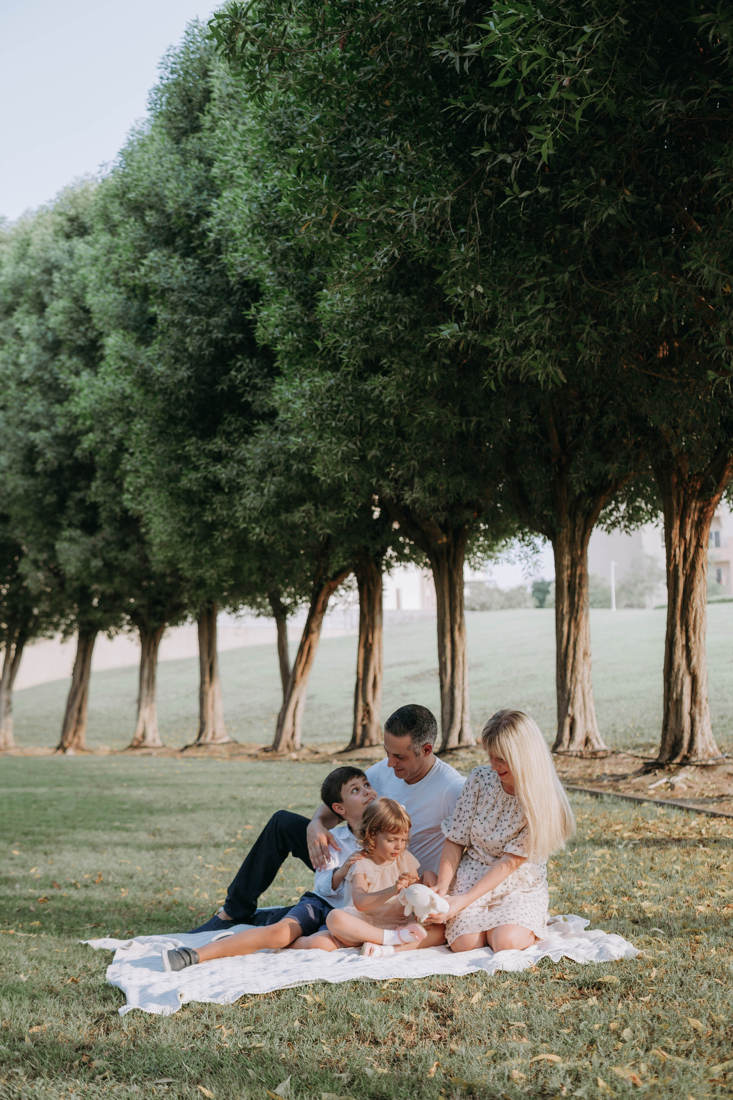 Family enjoying a picnic under trees in a park