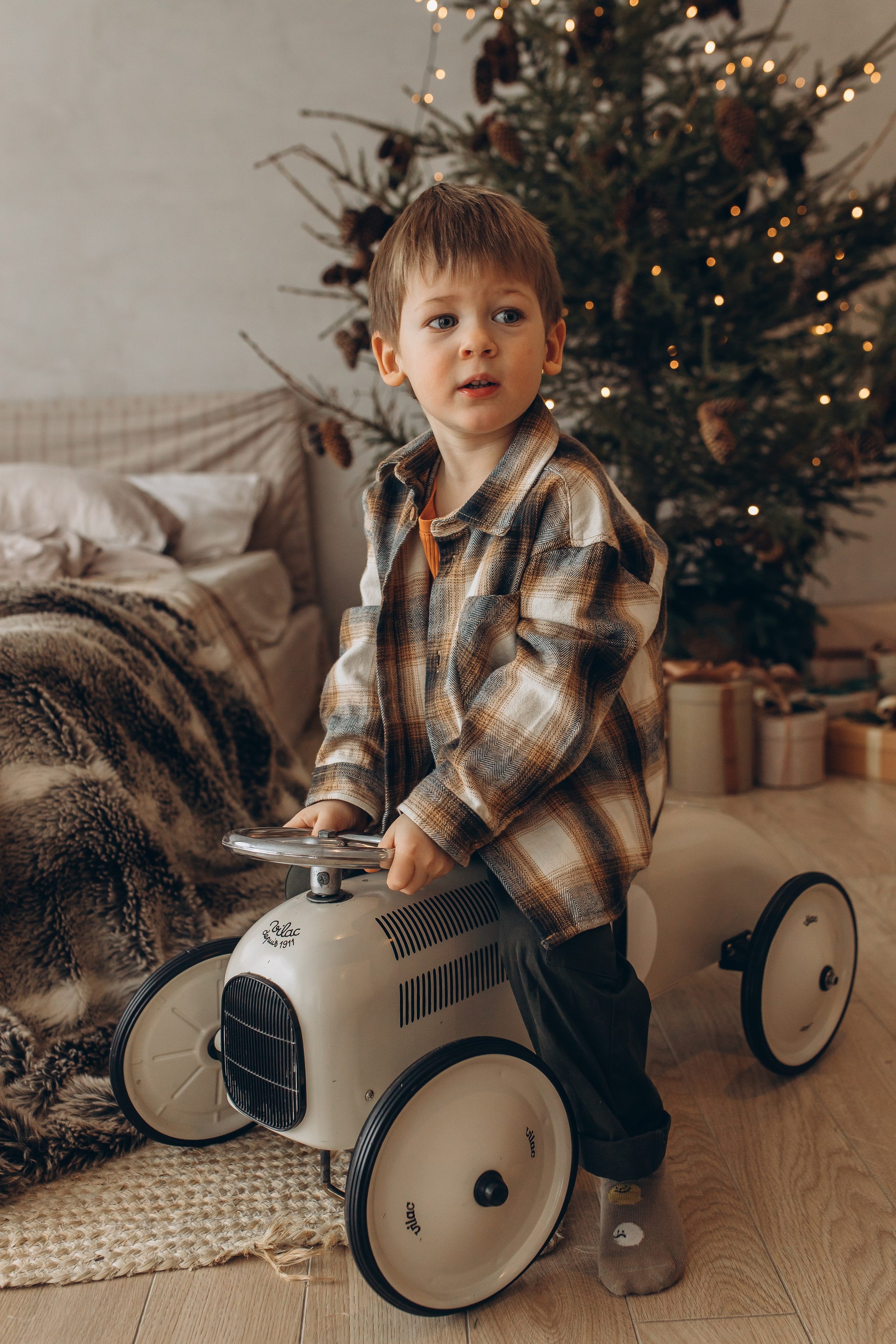 Счастливая семья в новогоднем интерьере с елкой сидит на белой лестнице и обменивается подарками. Студийные праздничные фотосессии, фотограф Маруся Самылкина в Санкт-Петербурге.