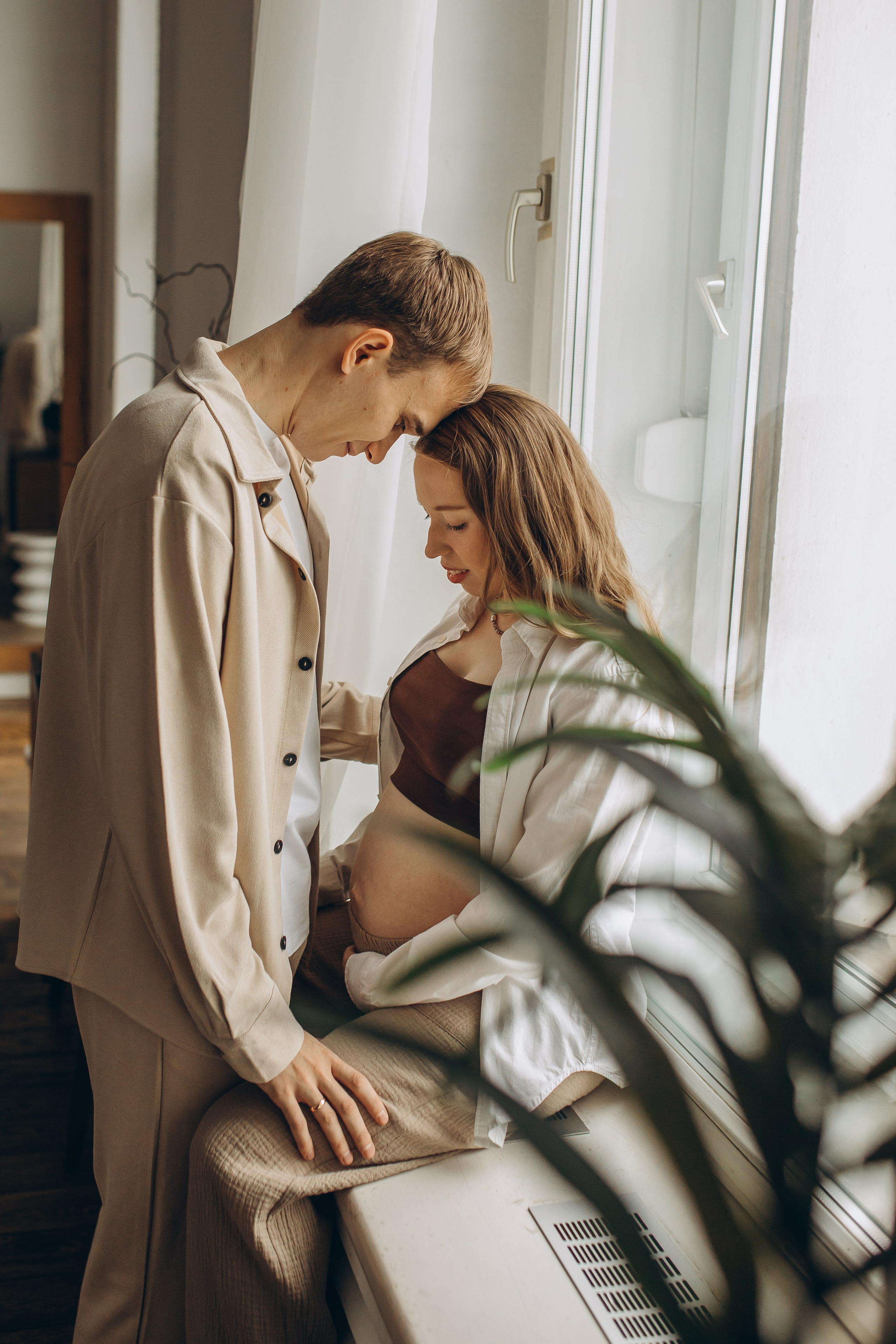 Близость между будущими родителями, нежный кадр пары в ожидании малыша в светлом интерьере. Фотосессии для беременных в Санкт-Петербурге, фотограф Маруся Самылкина.