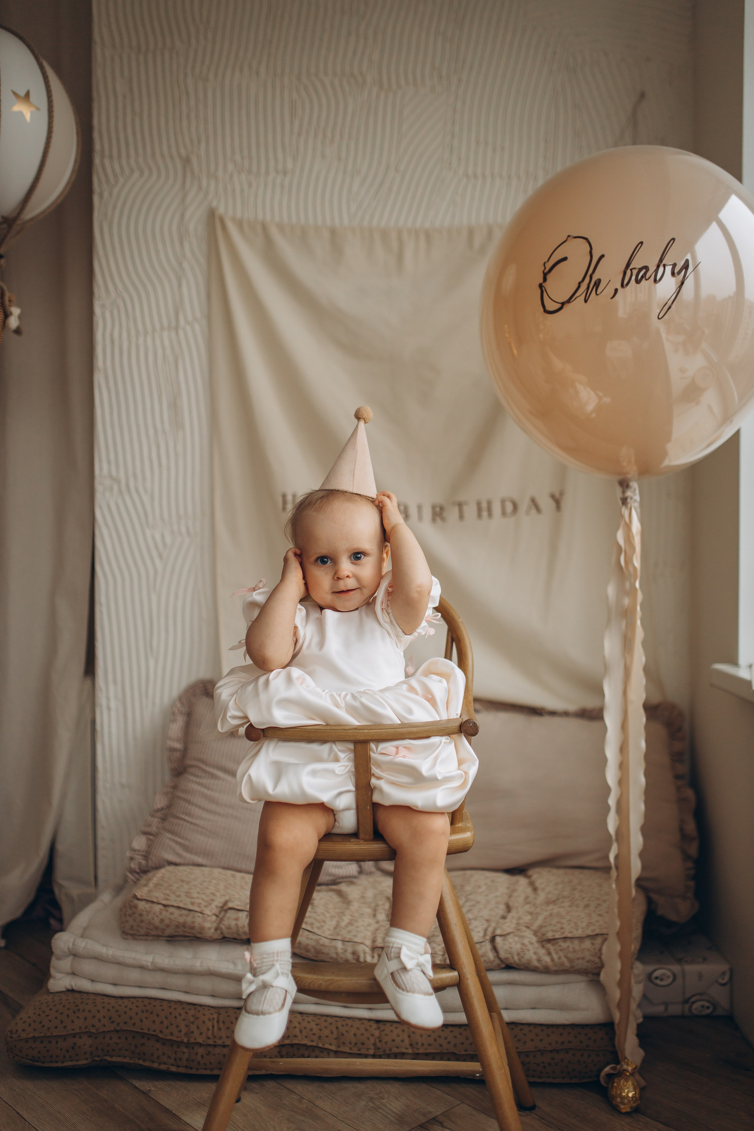 Маленькая девочка с белыми бантиками игриво позирует в свой день рождения. Детский фотограф Маруся Самылкина, Санкт-Петербург.