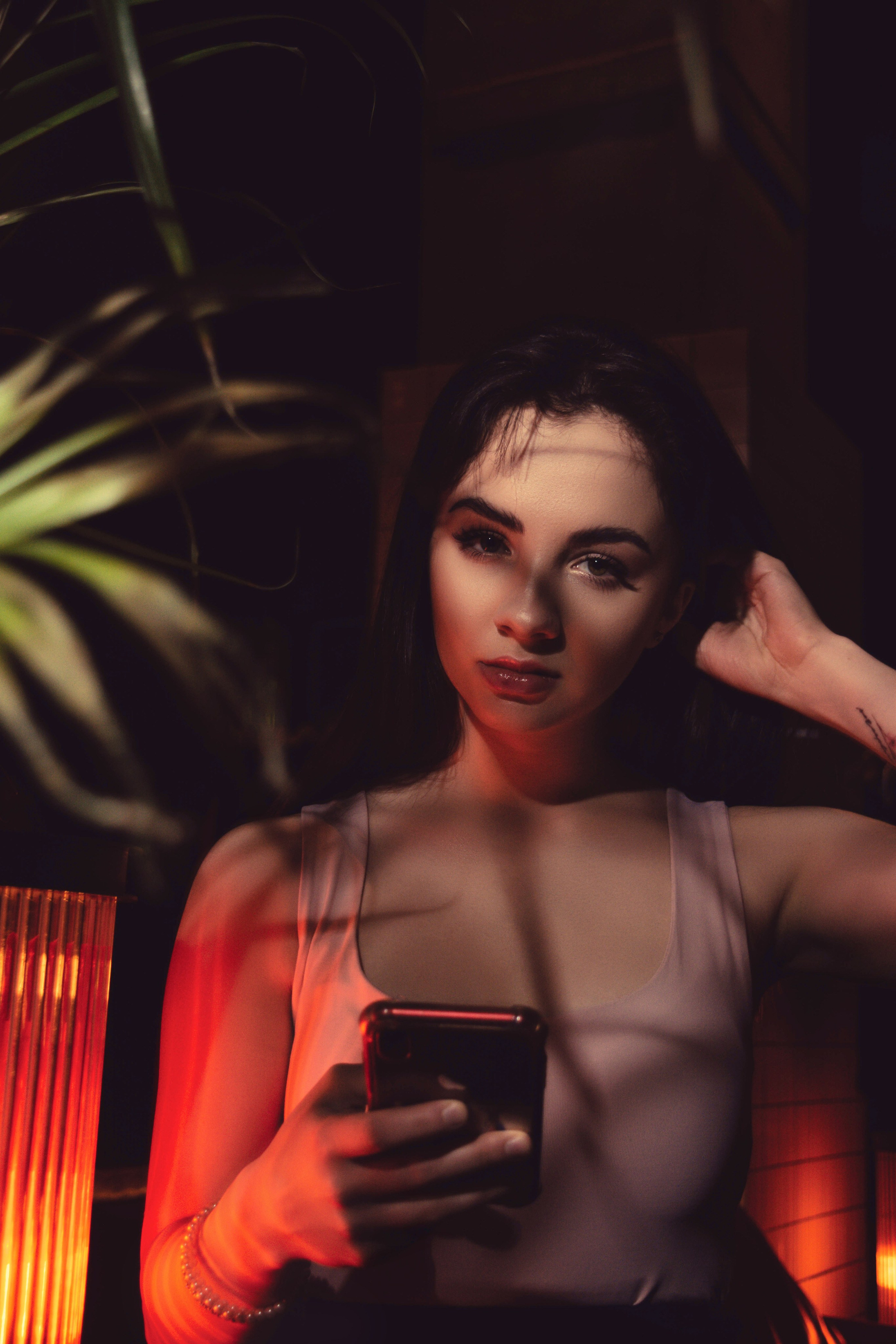 A woman holding a smartphone under dramatic lighting, ideal for showcasing the connection between technology and visual marketing strategy.