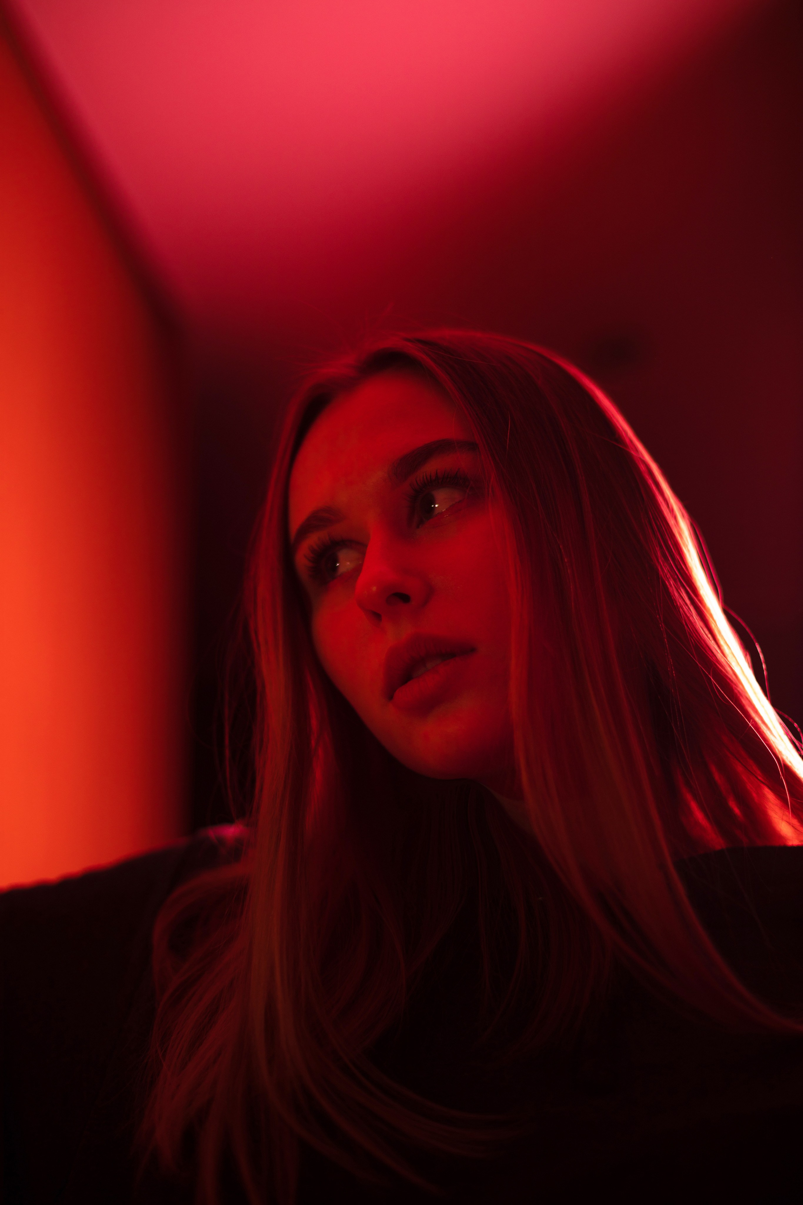 Close-up of a woman with a red-lit background, showcasing emotional portrait photography for brand storytelling in social media marketing.