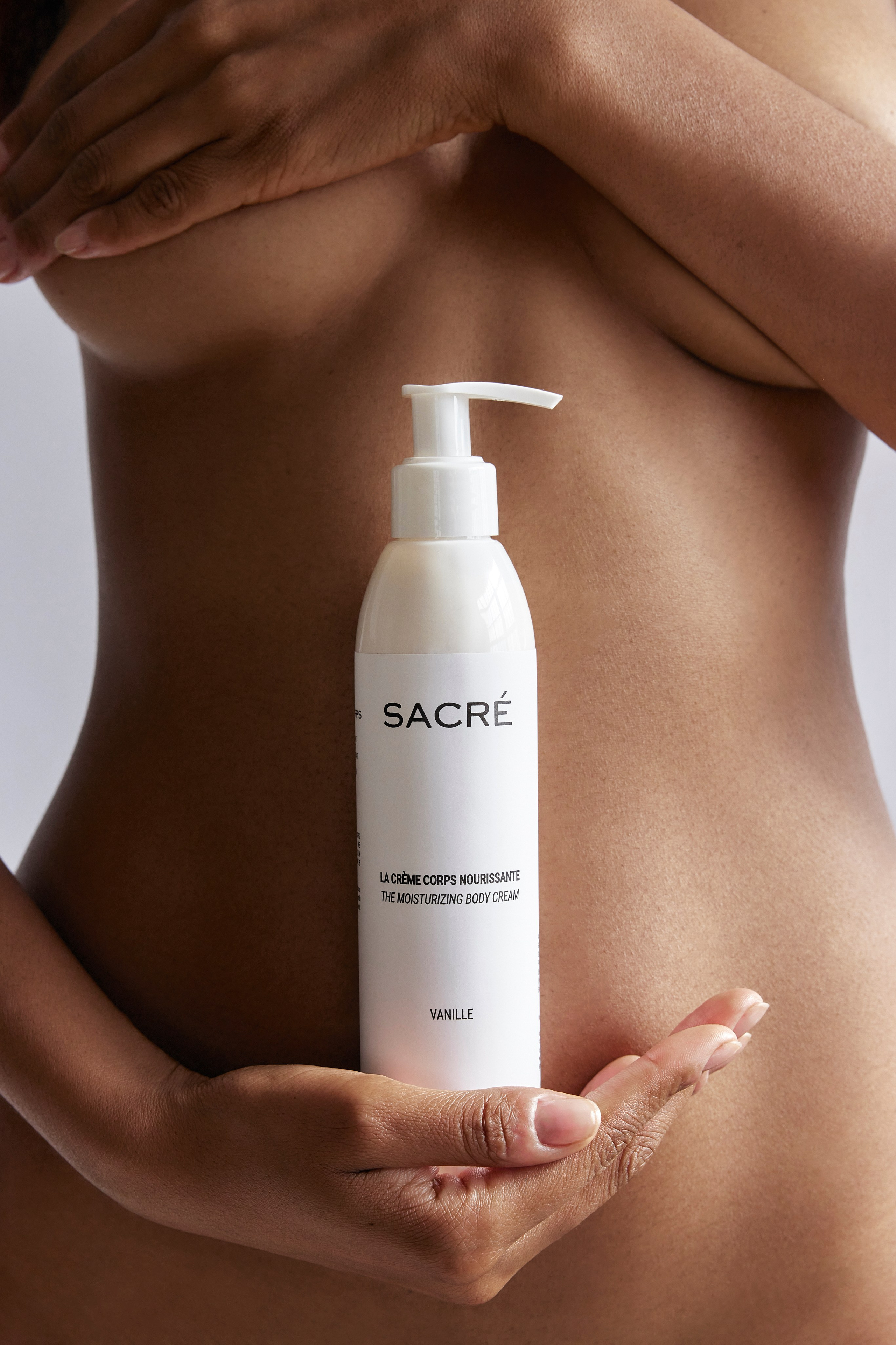 Model holding Sacré moisturizing body cream, emphasizing natural beauty, self-care, and the elegance of women in a skincare campaign