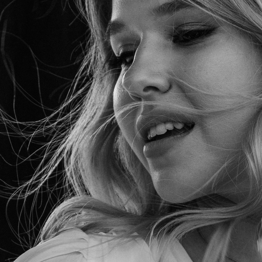 Невеста улыбается и смотрит в сторону с букетом в руках на съёмке утро невесты