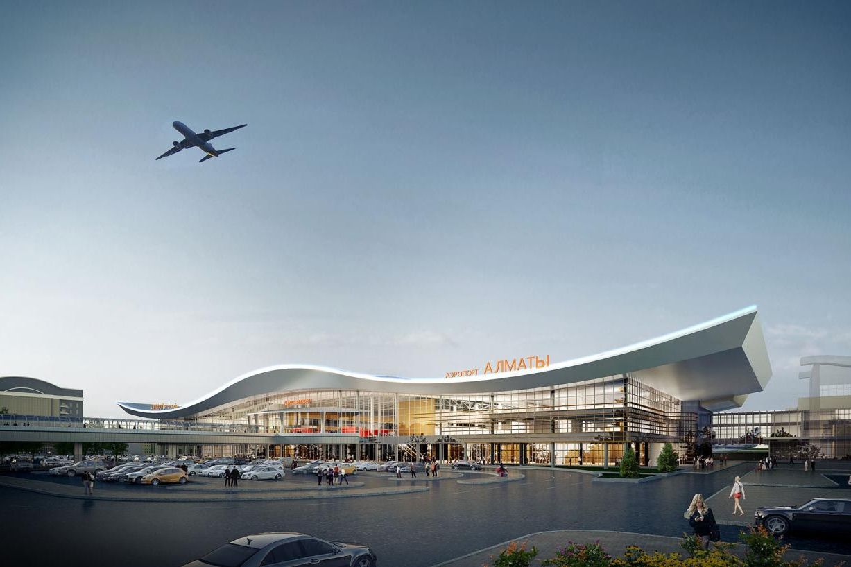 Вид на Лунный Каньон реки Чарын недалеко от Алматы, окружённый зелёными деревьями и кустарниками, на фоне красочных скал в солнечный день. На переднем плане женщина сидит на утёсе и любуется пейзажем