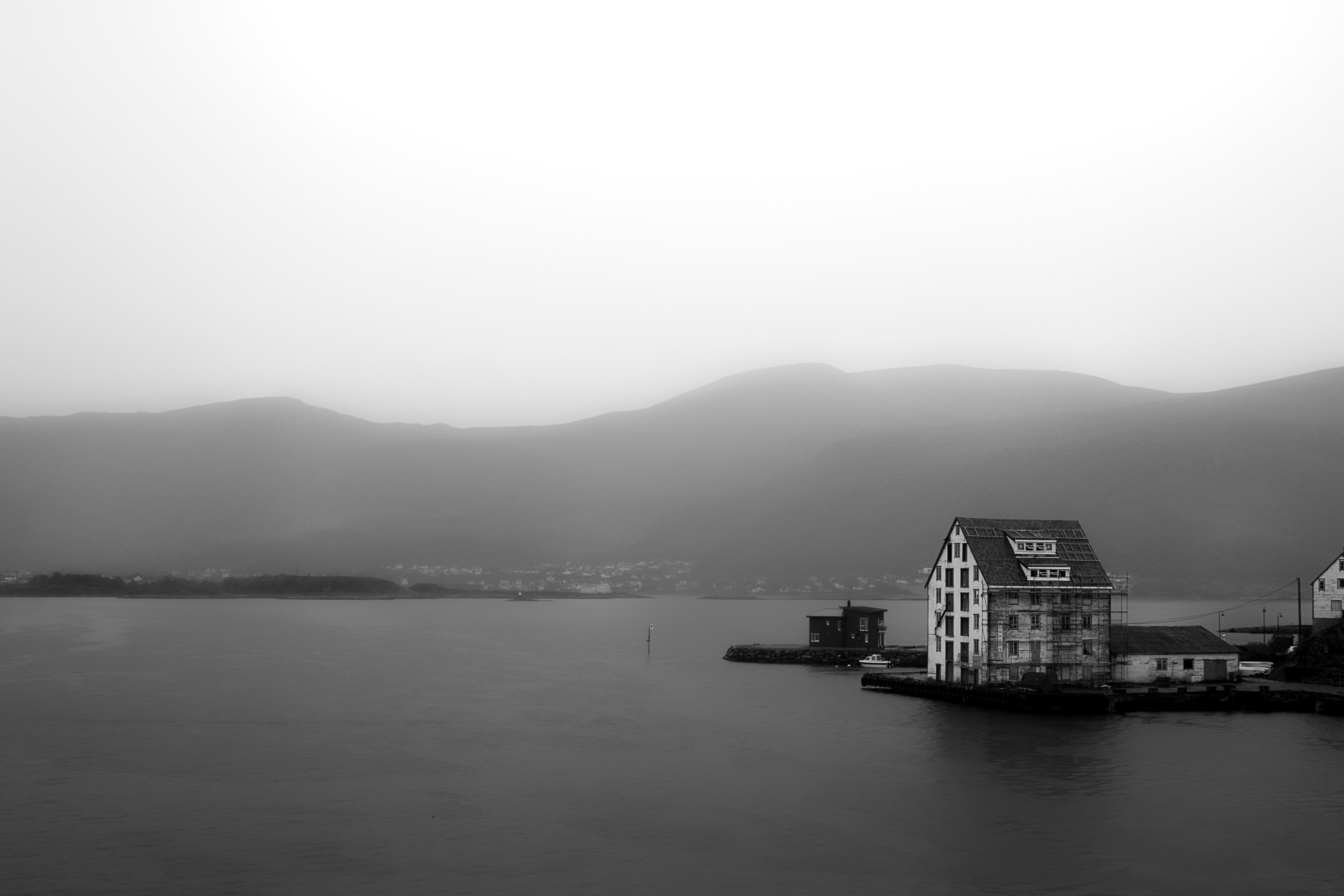 Дома на воде в тумане, горы на заднем плане, минималистичный черно-белый пейзаж фьорда
