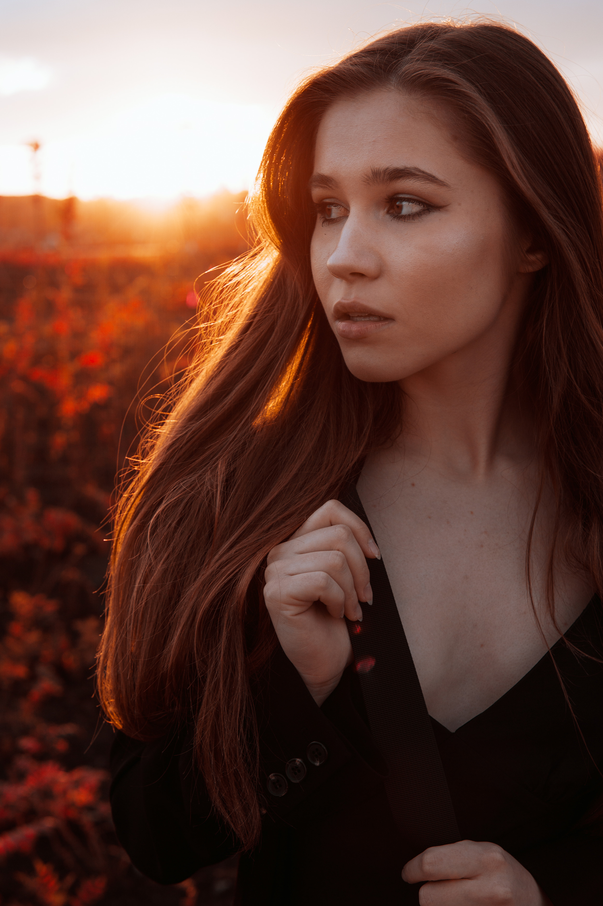 Портрет молодой красивой девушки на фоне поля и красного заката