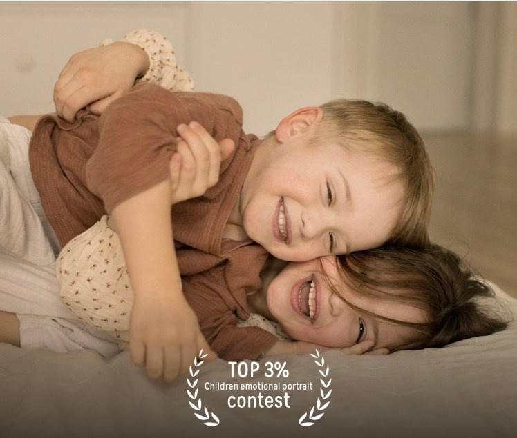 Девочка и мальчик обнимаются и смеются лежа на кровати.