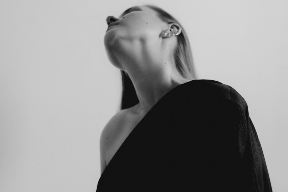 Снимок девушки в по пояс сбоку на фоне белой стены