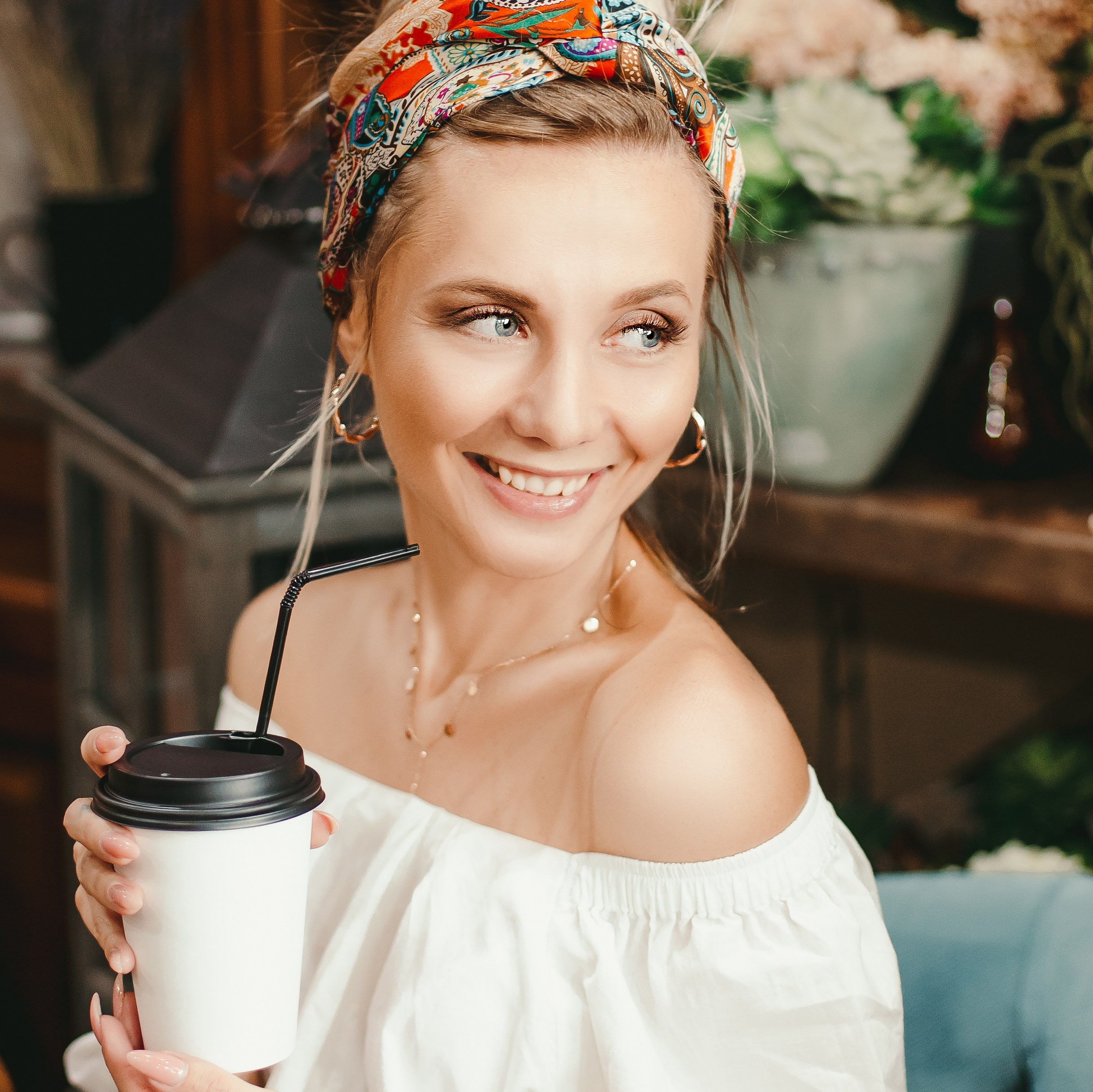 красивая девушка фотографируется в кафе со стаканом кофе в мягком кресле