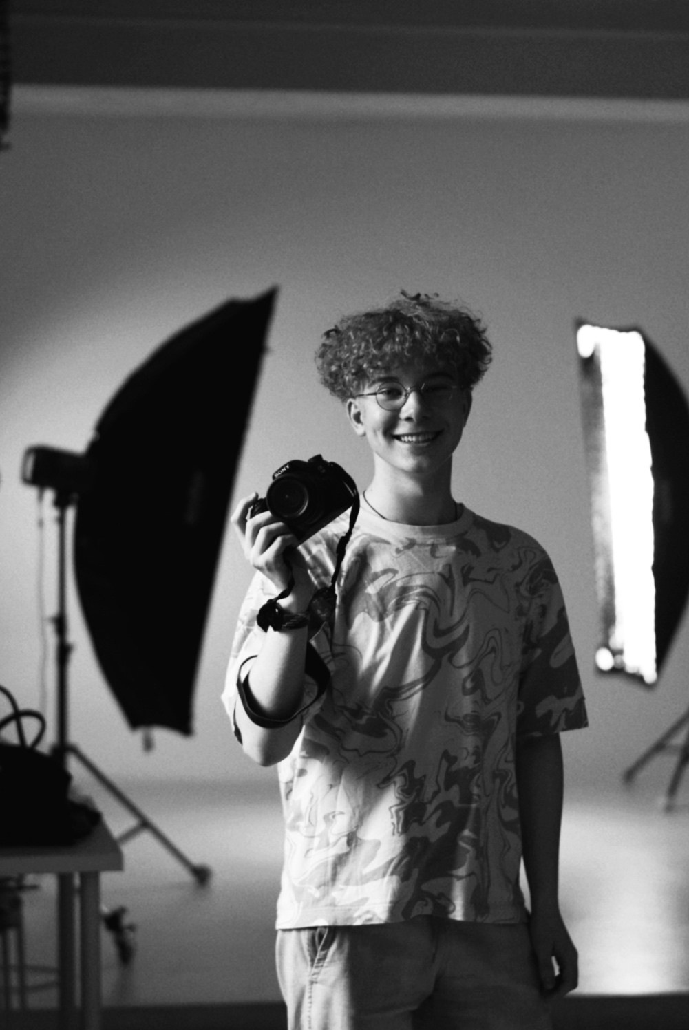 молодой человек с кудрявыми волосами на лестнице креативного музея в Санкт-Петербурге, чёрно-белая художественная фотография с архитектурной композицией