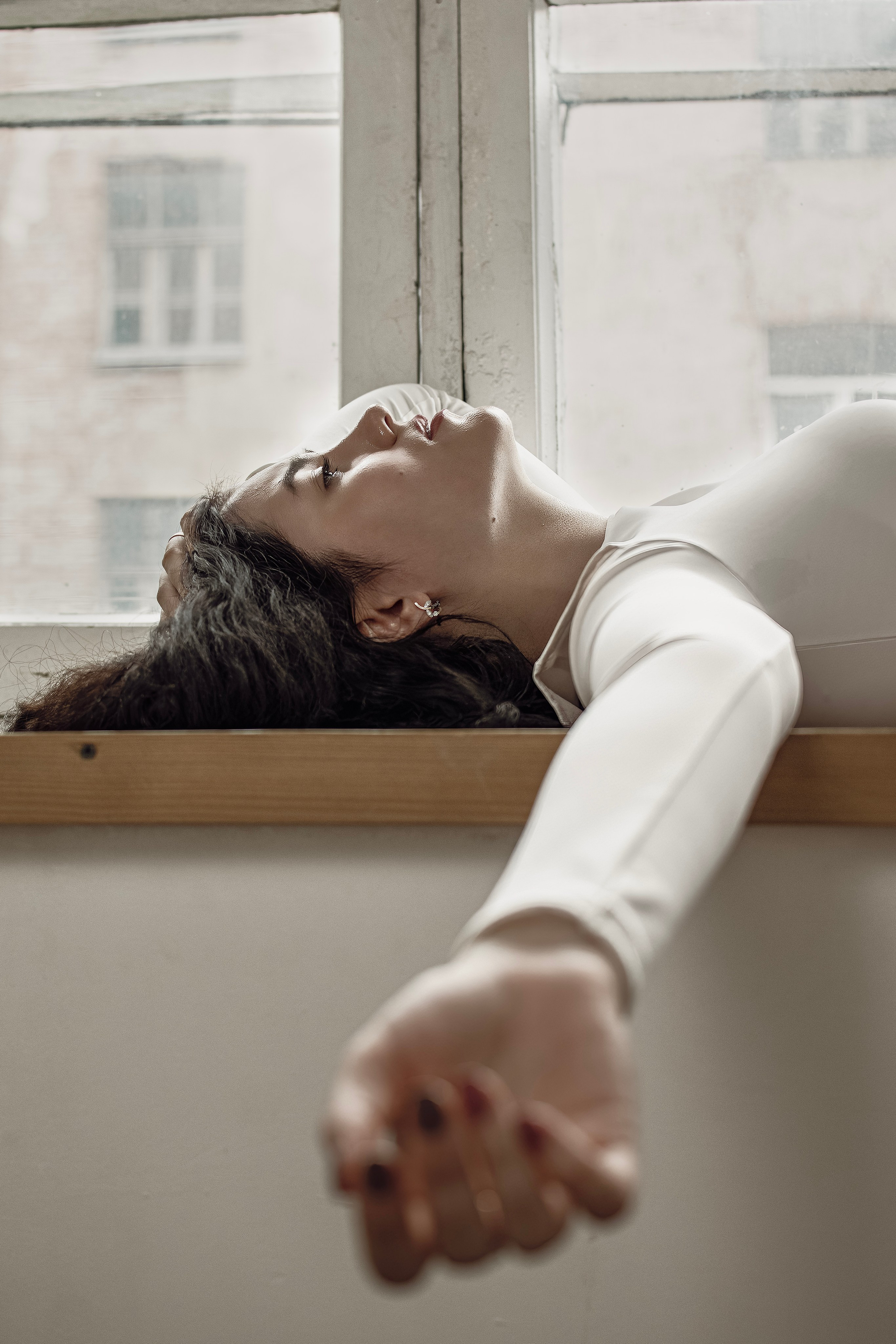 Фотография девушки лежащей у окна на едине со своими мыслями.