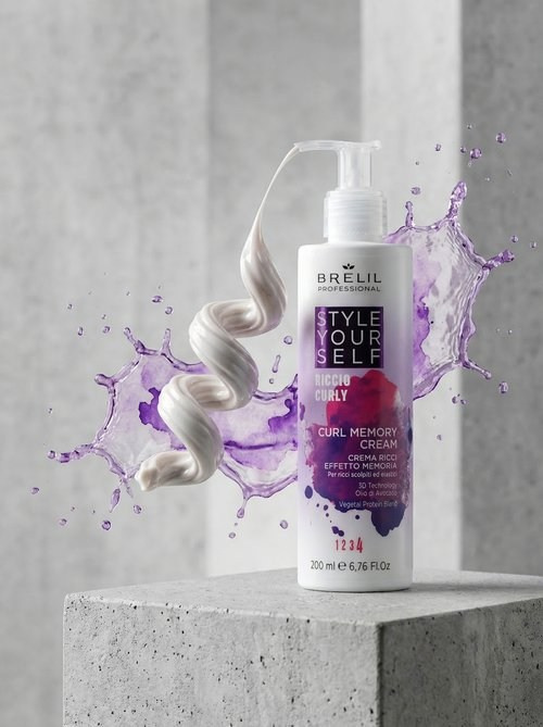 Флакон стоит на гладком бетонном подиуме. Из дозатора выходит капля крема, застывшая в виде идеальной, упругой пружинки-локона