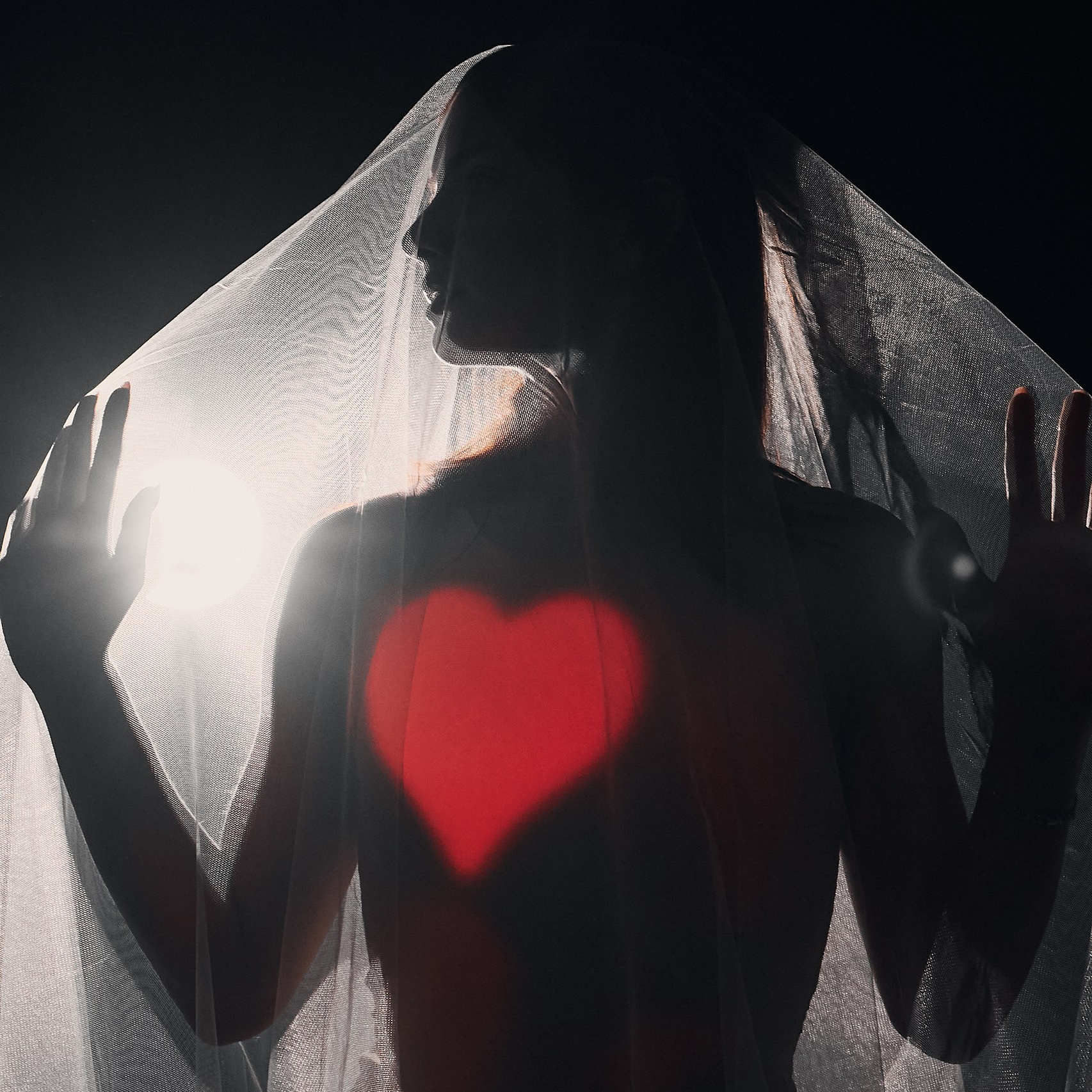 Студийный портрет в классическом стиле: женщина в черном корсете и длинных черных перчатках, с жемчужным ожерельем и серьгами, задумчиво смотрит в сторону.