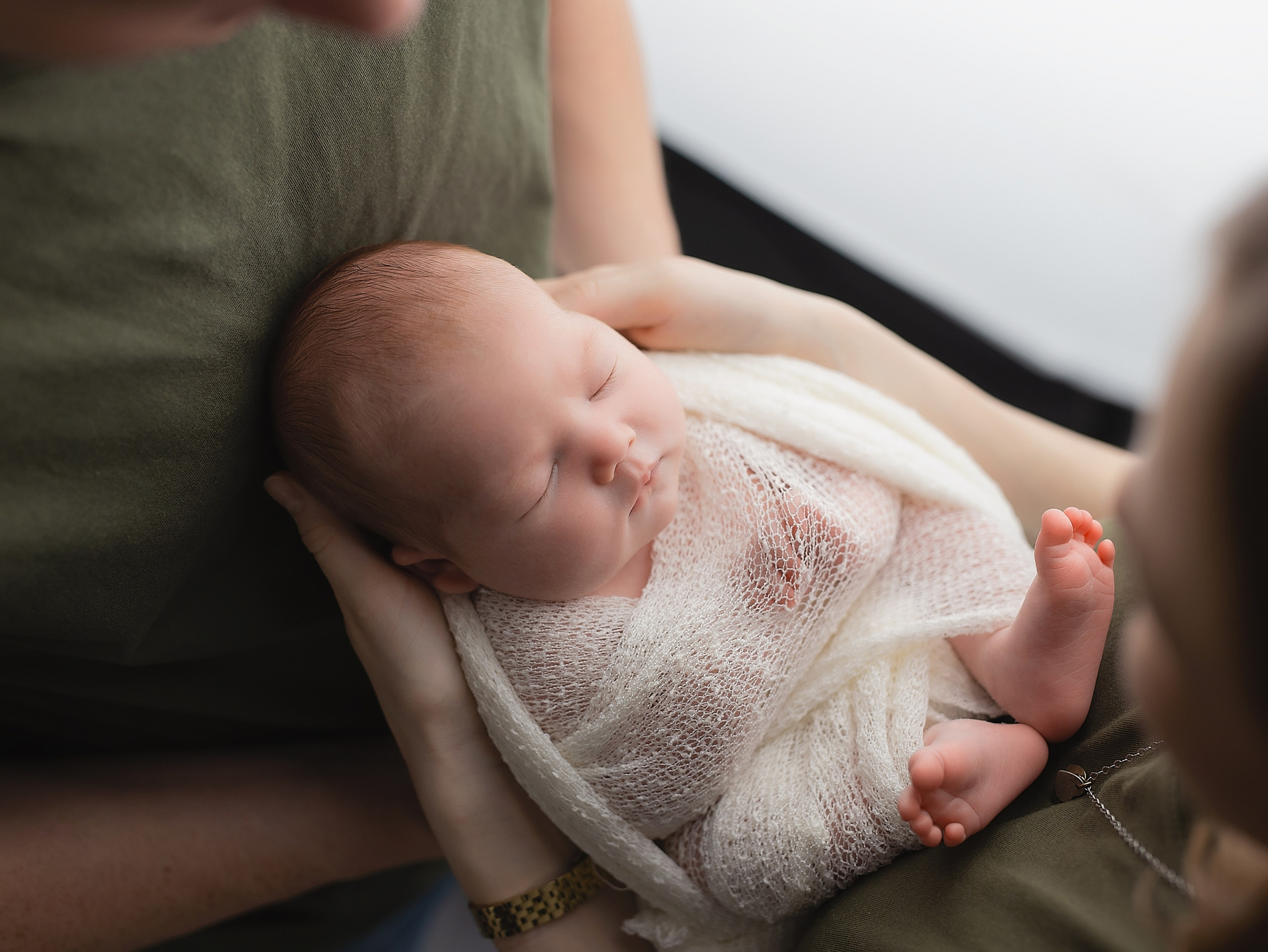 Фотосессия новорожденного в красивой обмоточке на руках родителей 