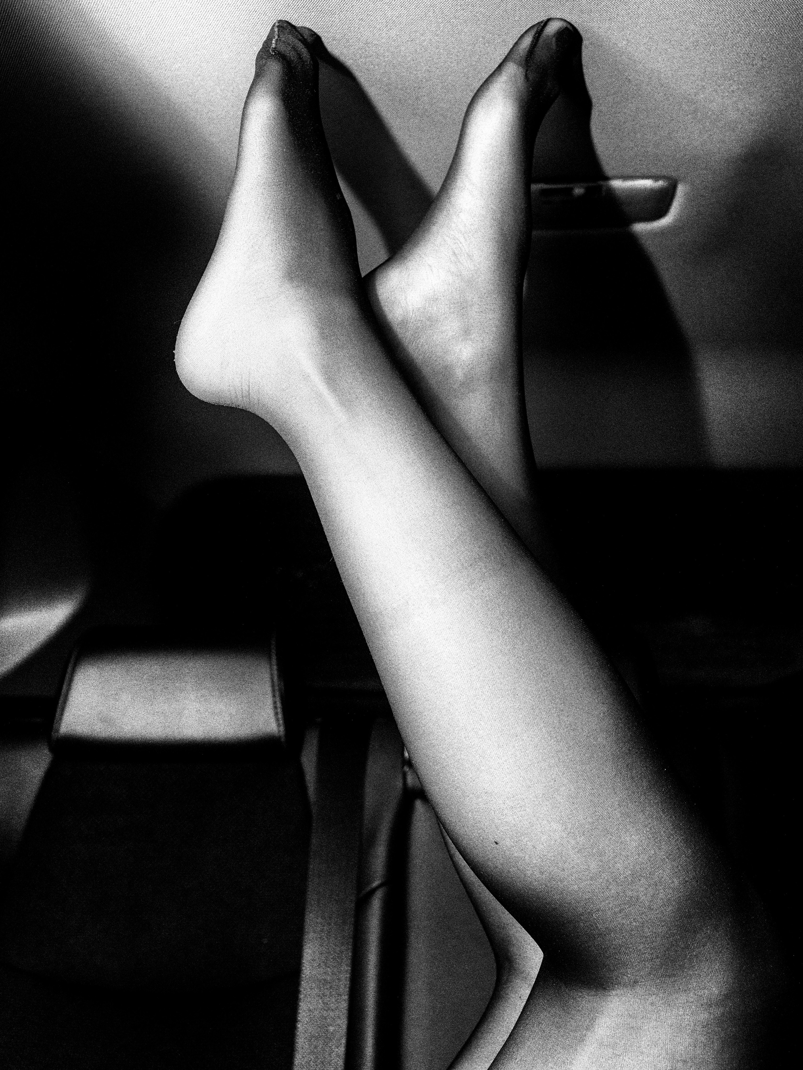 Женские стройные ножки в черных колготках упираются в крышу салона машины.