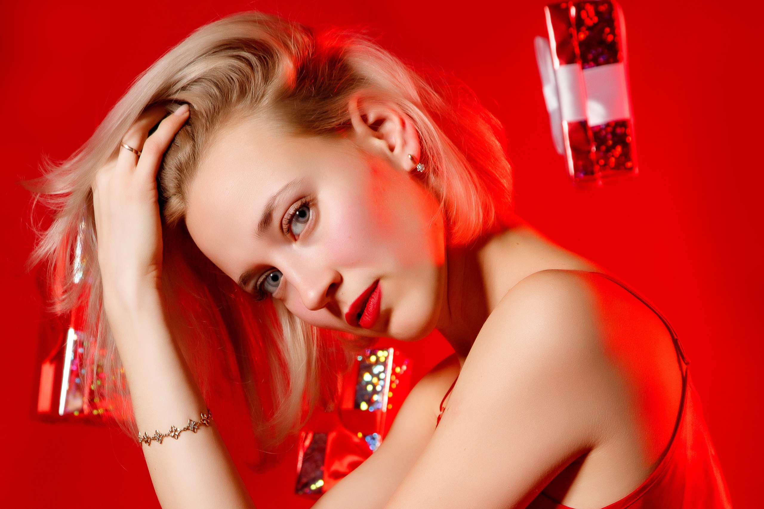 Яркая красивая накрашенная блондинка позирует на красном фоне