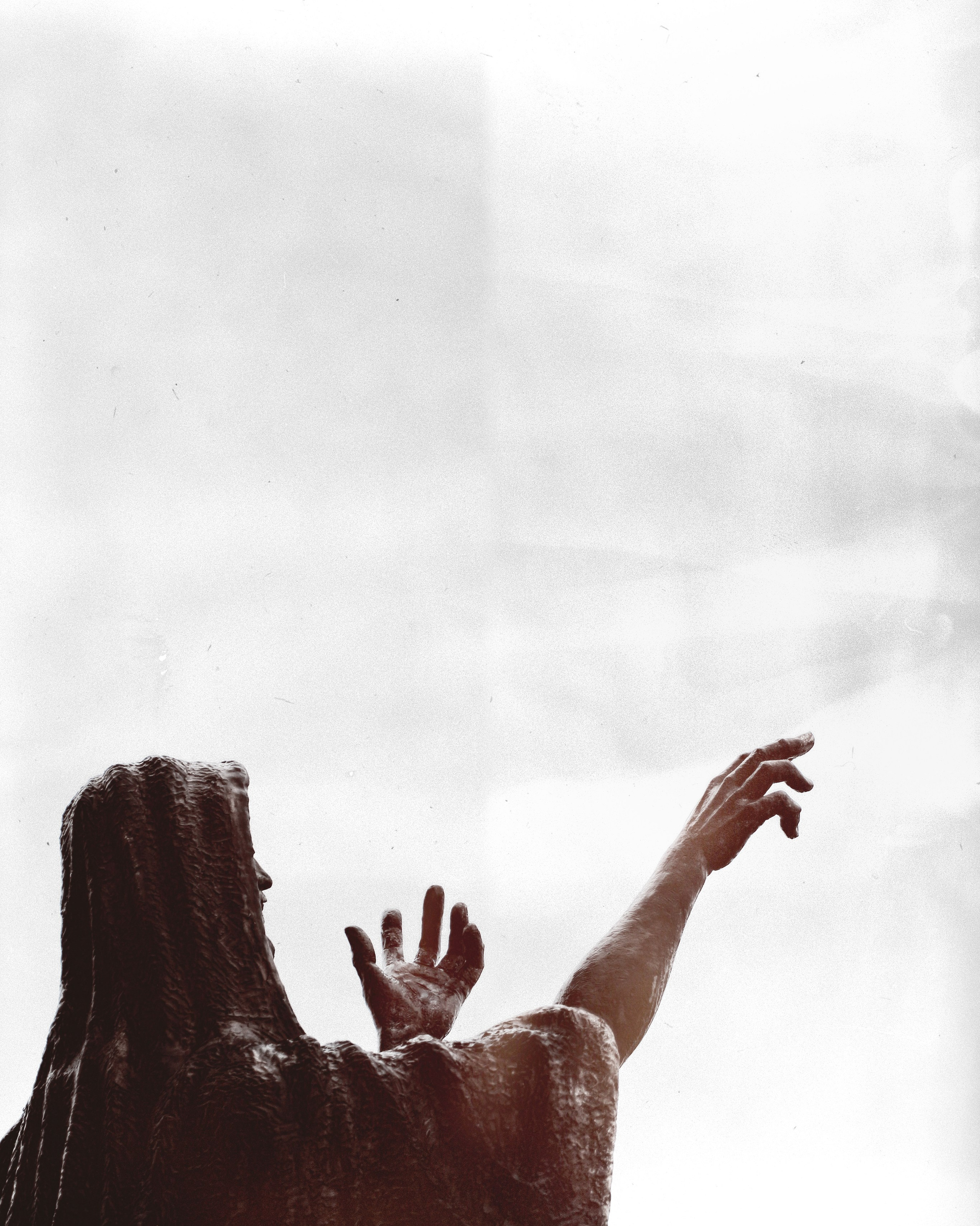 Минималистичный силуэт фигуры с поднятыми вверх руками, высококонтрастное черно-белое фото, драматичная композиция