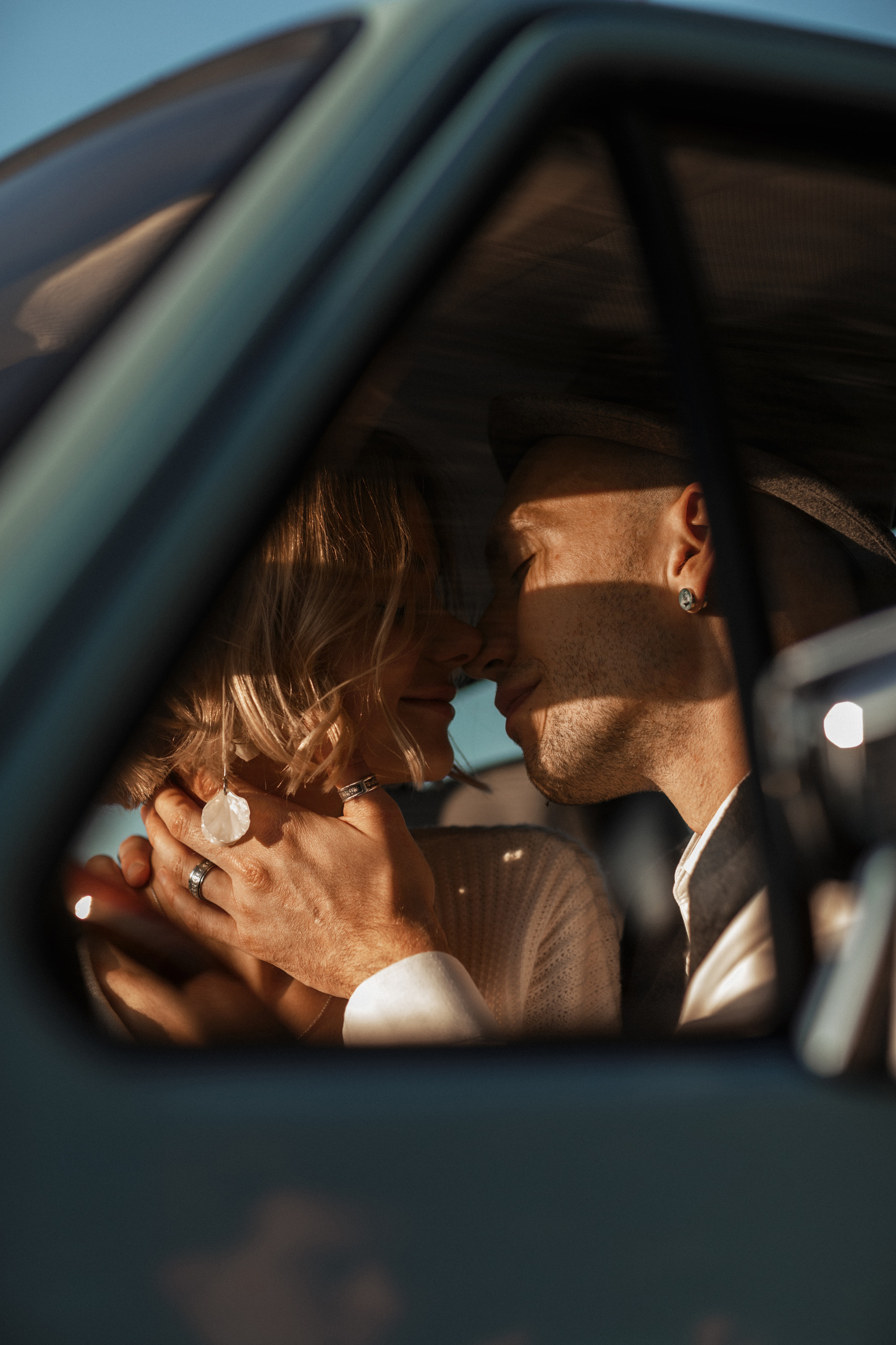 Жаркие и нежные поцелуи пары в машине в лучах закатного солнца.