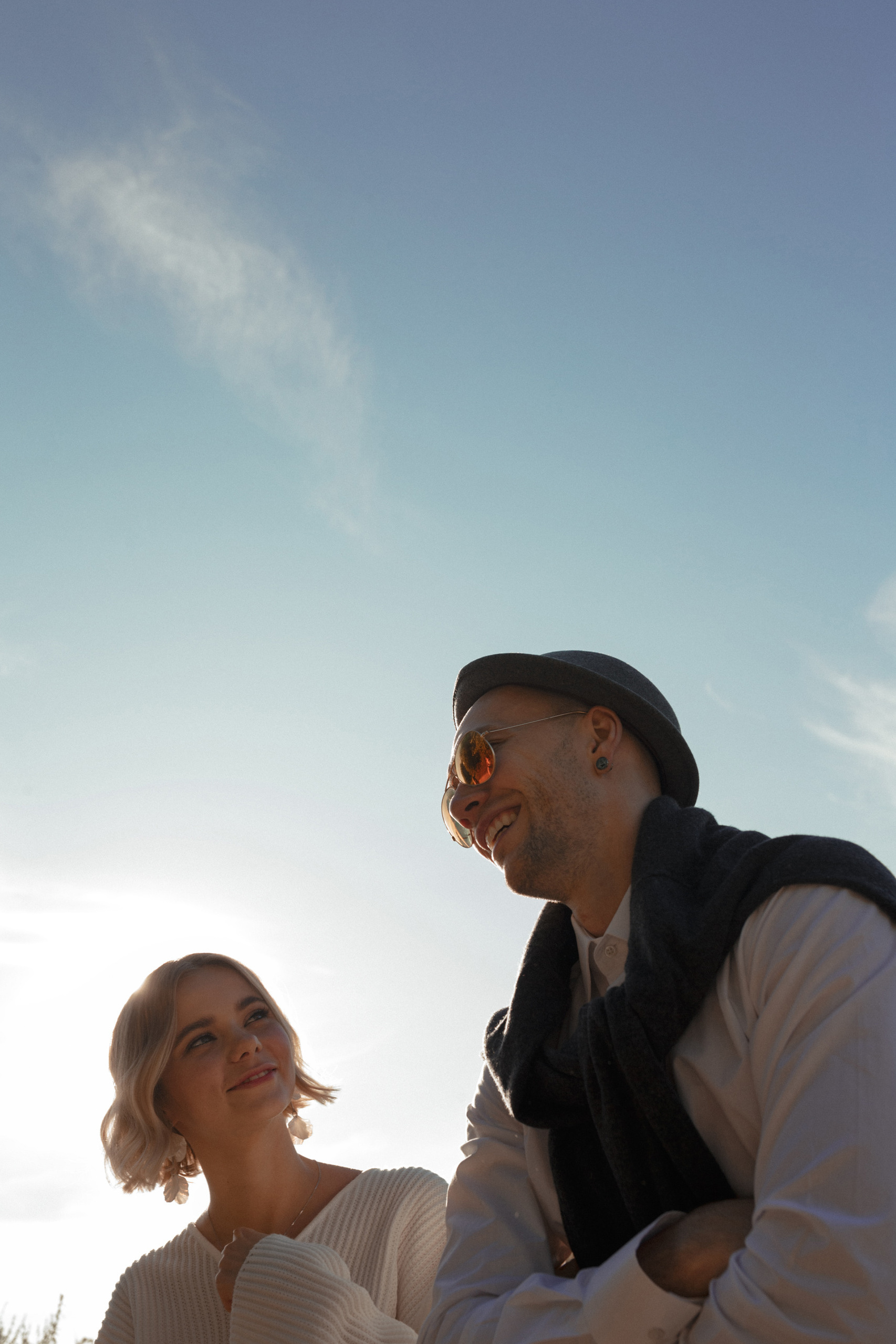 Жених и невеста, пара, смотрят на голубое небо, улыбаясь друг другу.