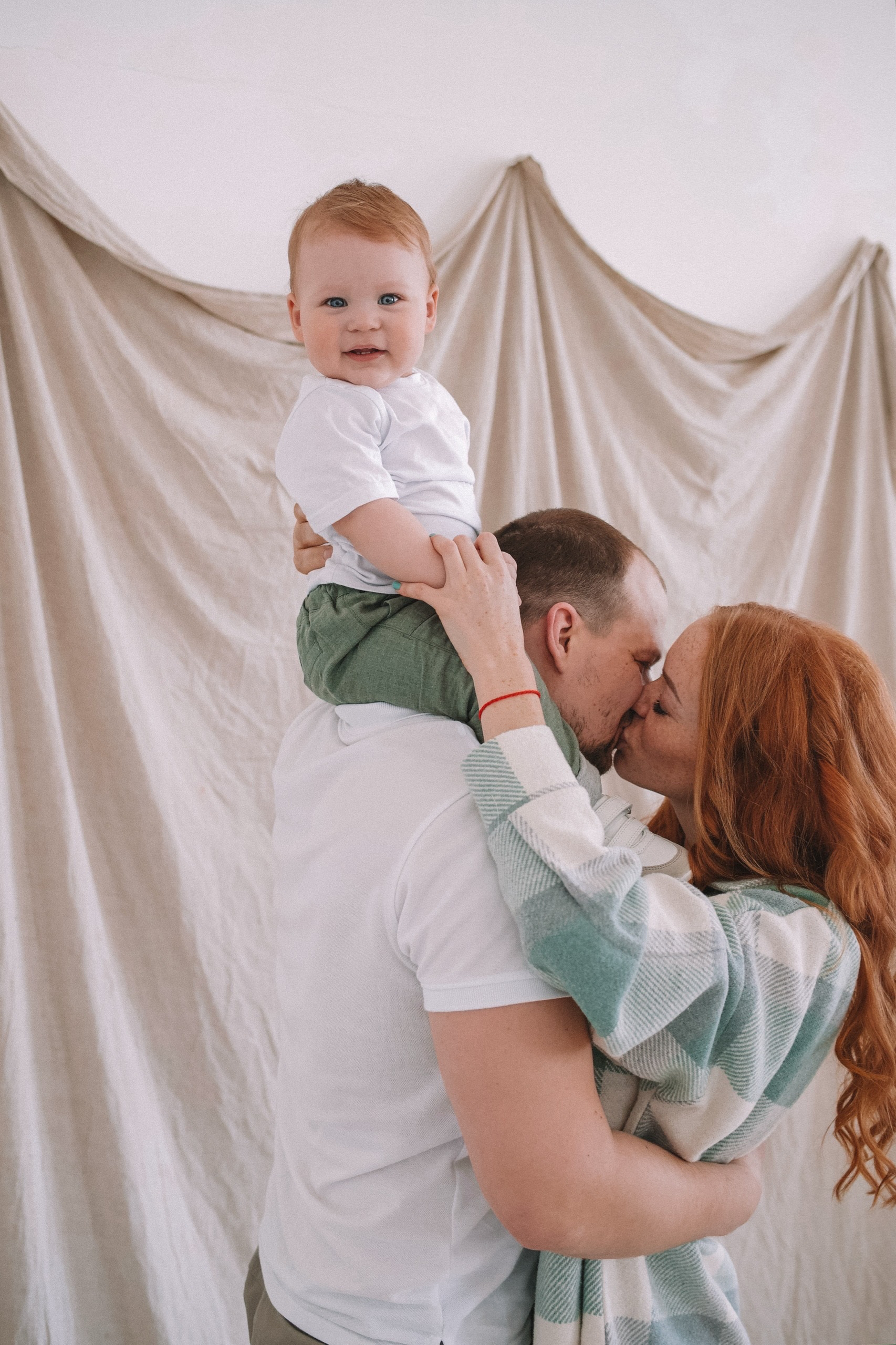 Семейная фотосессия в студии — родители держат ребёнка на руках