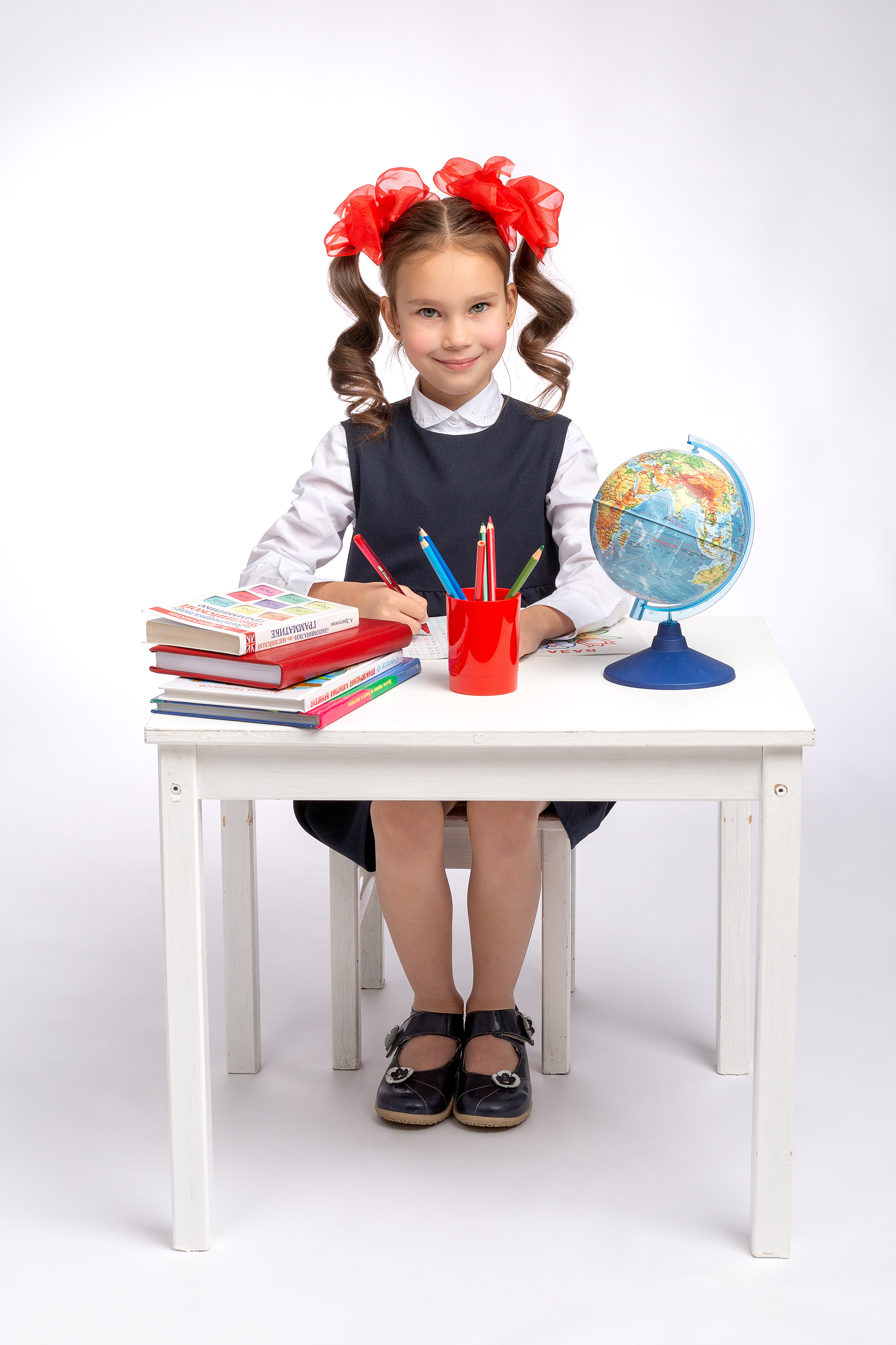 Девочка семи лет сидит за школьной партой.