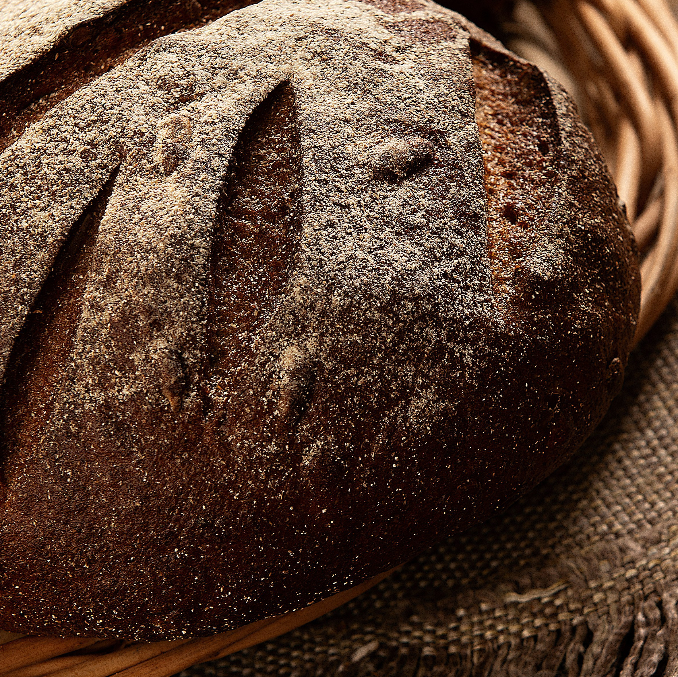 Свежий ржаной хлеб в плетёной корзине. Натуральная текстура корки и деревенская стилистика оформления.