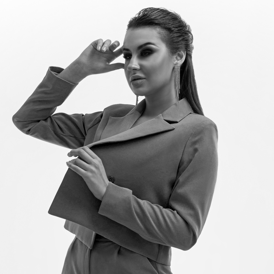 Девушка с длинными волосами в брючном костюме и туфлях на белом фоне