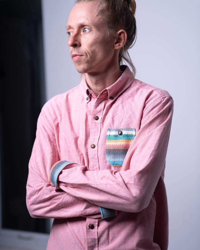 Женщина в традиционном Вьетнамском платье с веером, прикрывающим половину лица, в солнечном свете.