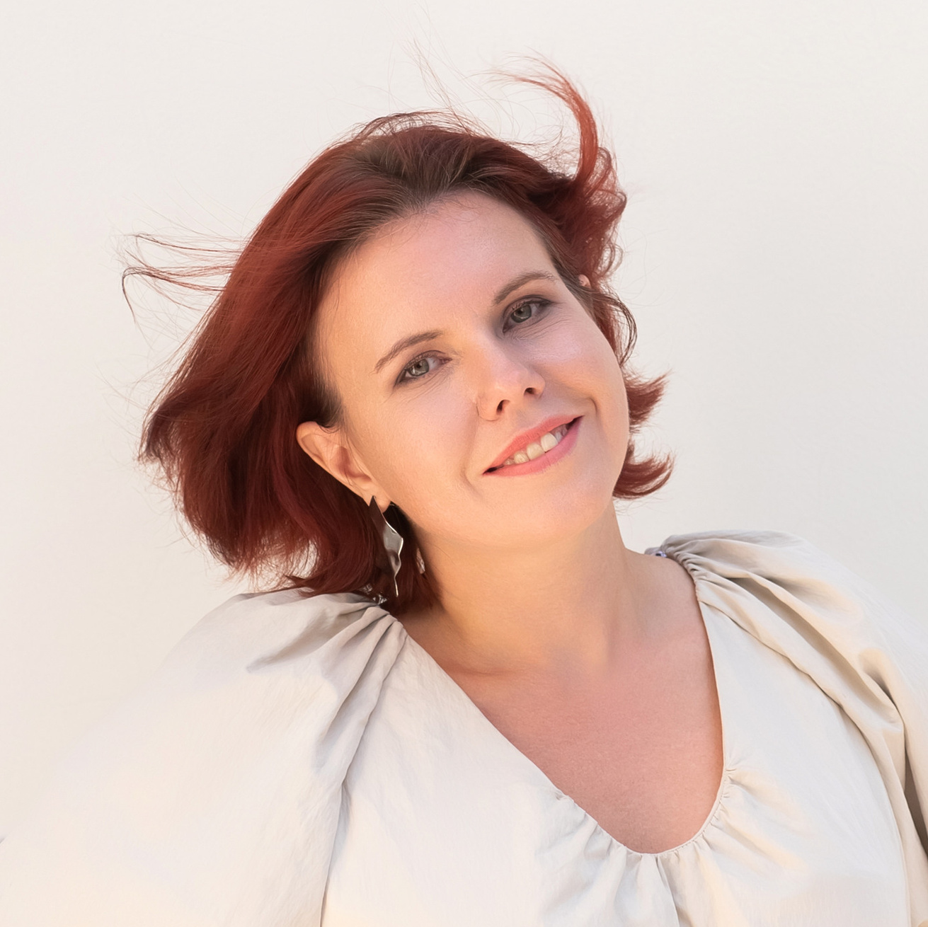 Девушка в бежевом платье смотрит в камеру и позирует