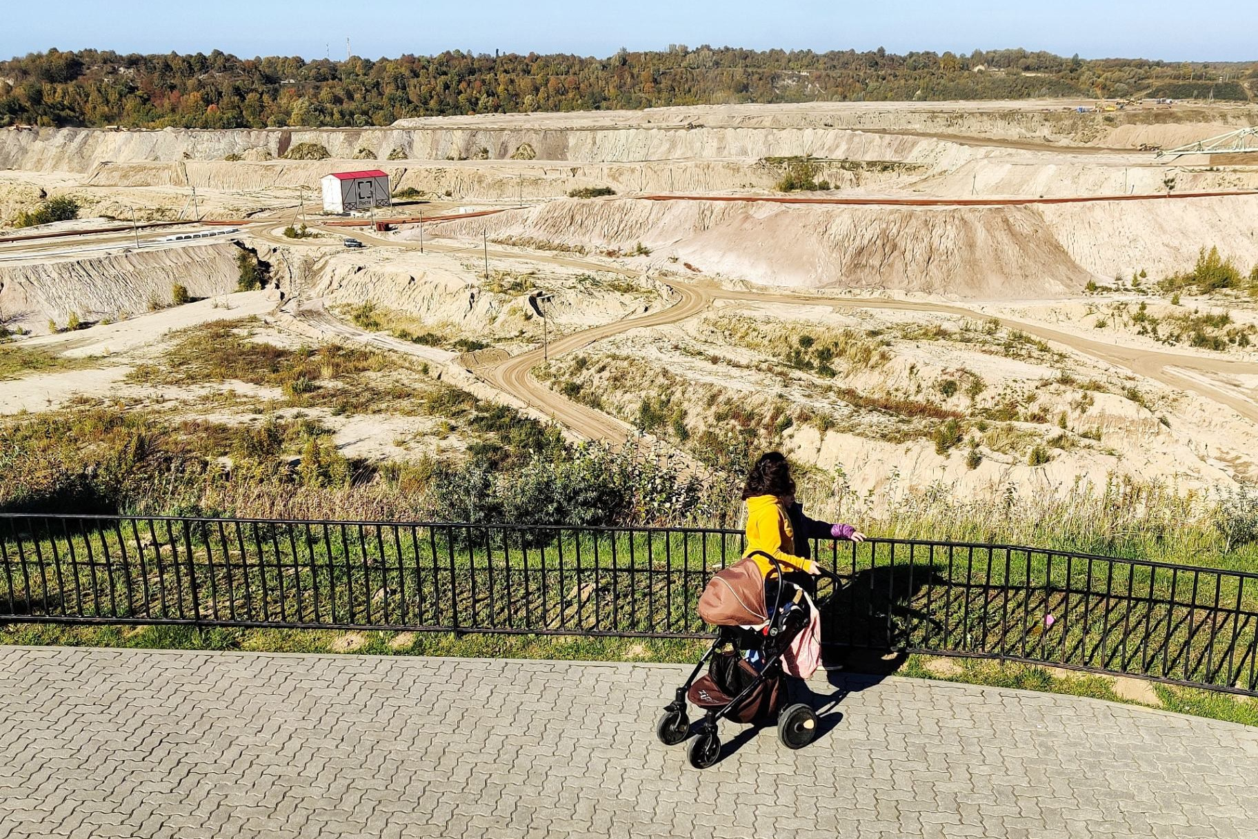 Женщина с коляской у смотровой площадки, открывающей панорамный вид на песчаный карьер в Калининградской области