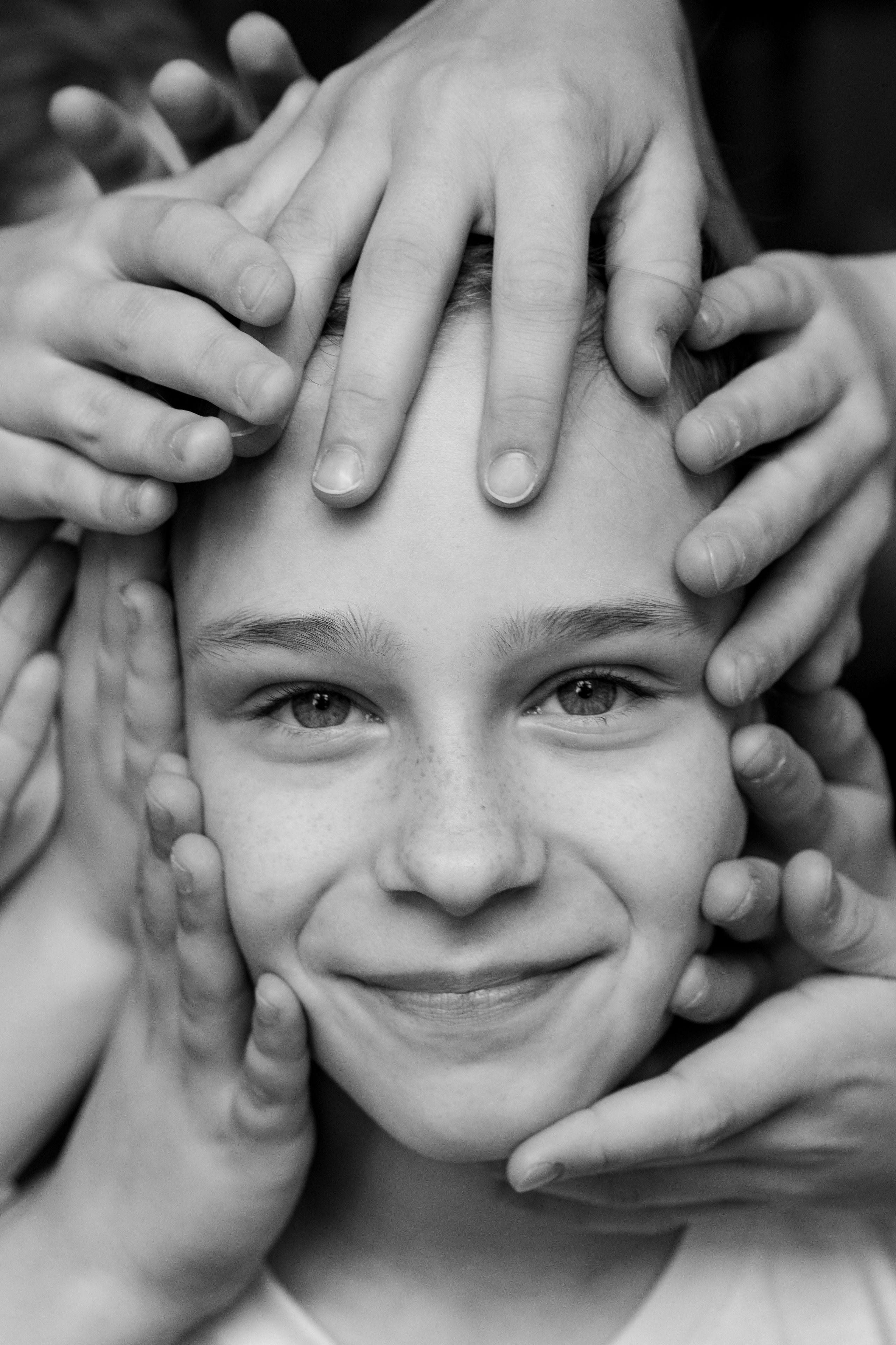 лицо юной гимнастки в окружении рук подруг чб