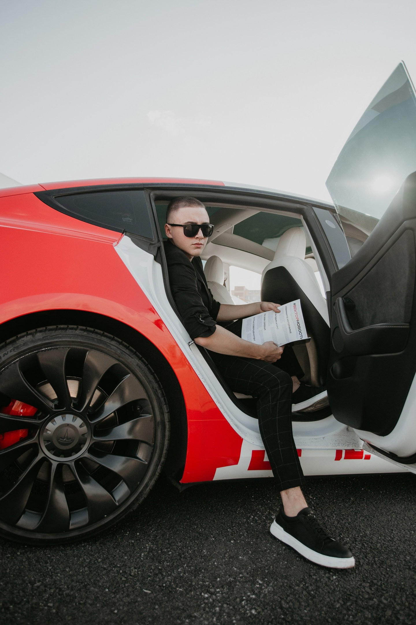 Уличная фотосессия: парень на заднем сидении машины держит журнал