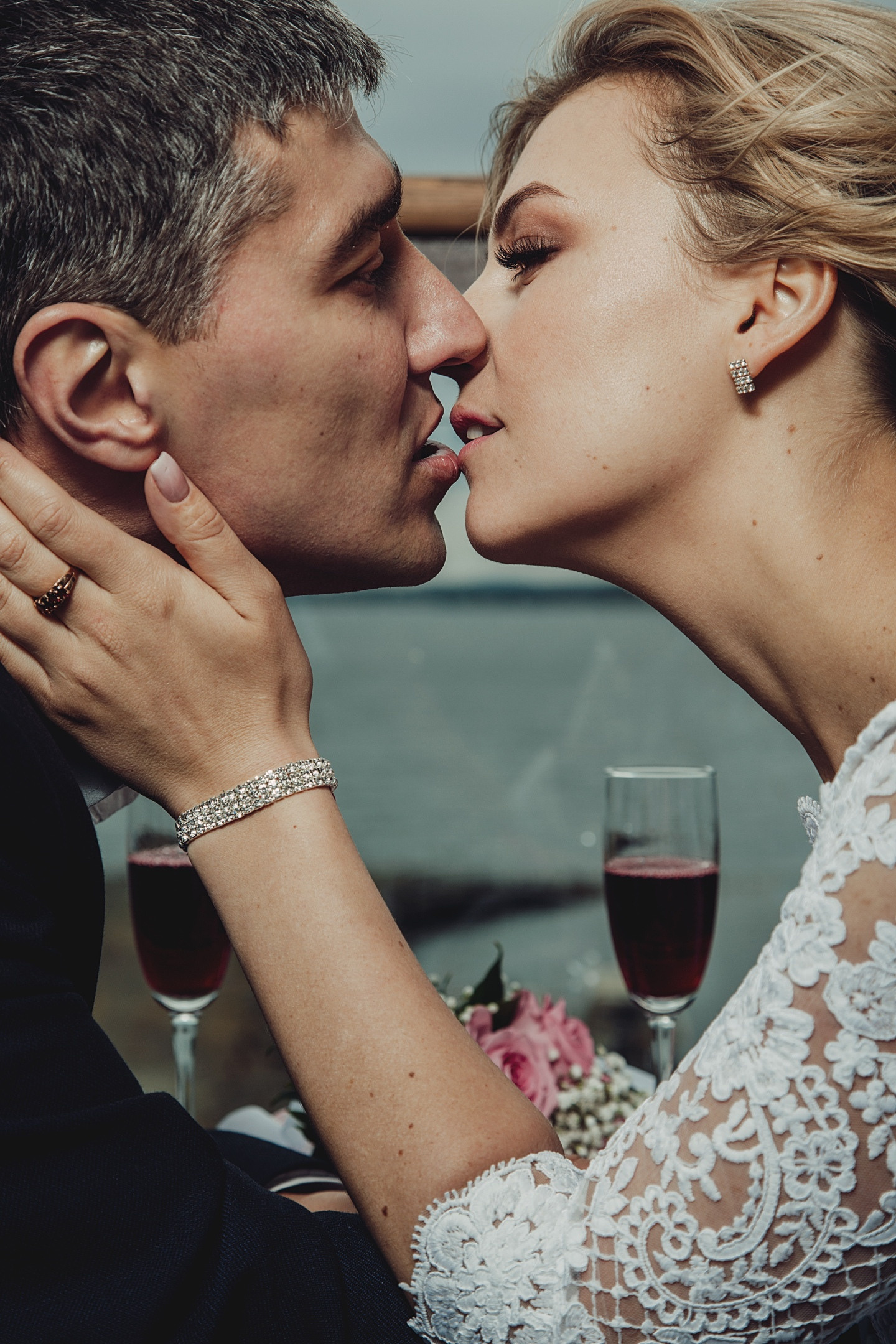 Молодожены целуются сидя за столом на улице