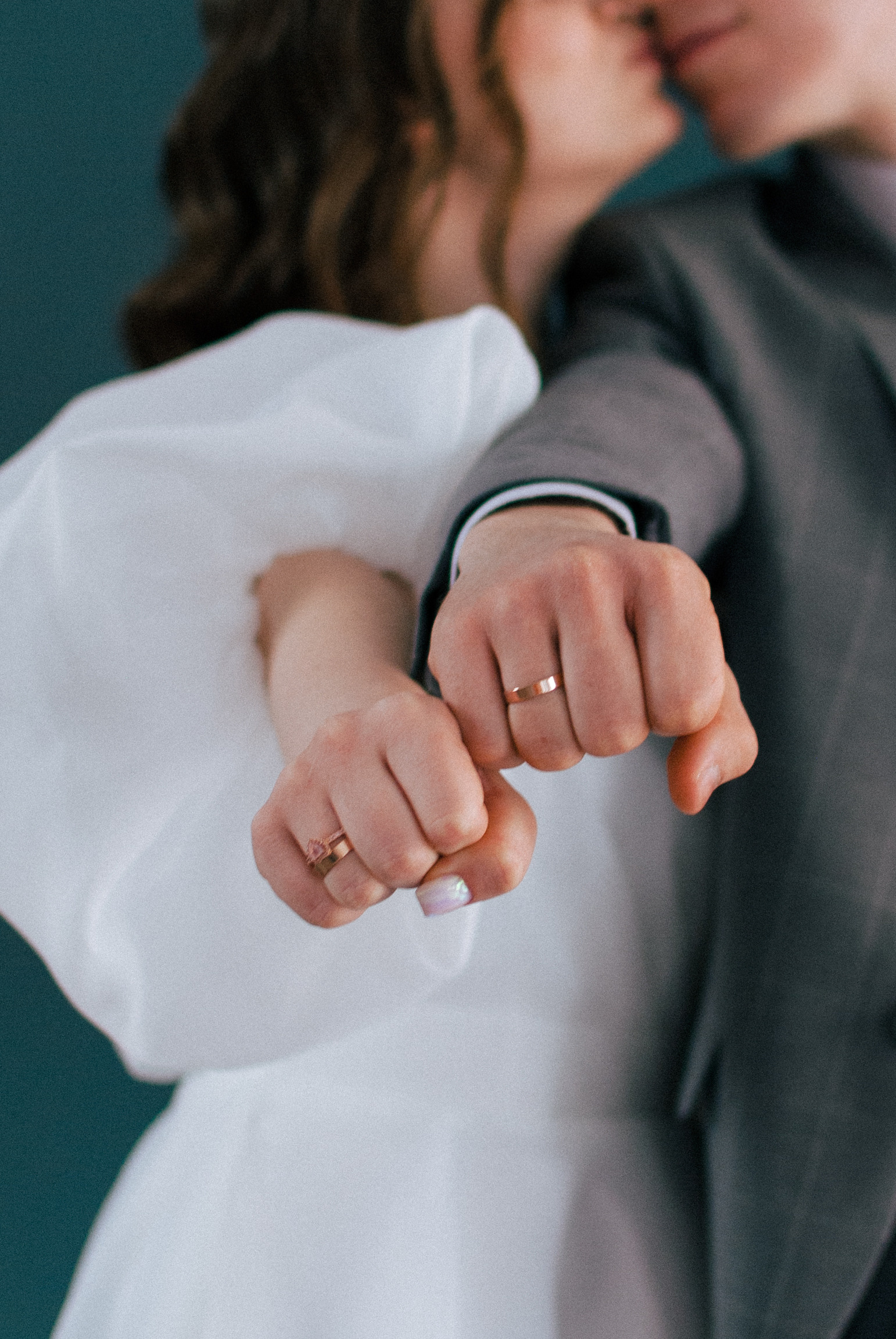 Жених и невеста показывают свои обручальные кольца и целуются в фотостудии.